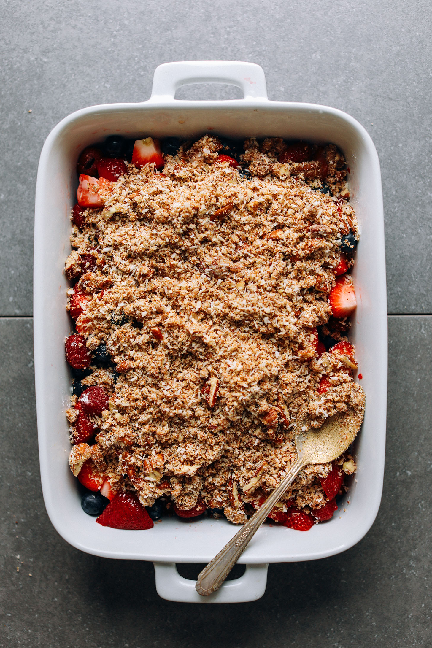 Grain-free crisp topping over fresh berries in a ceramic baking dish