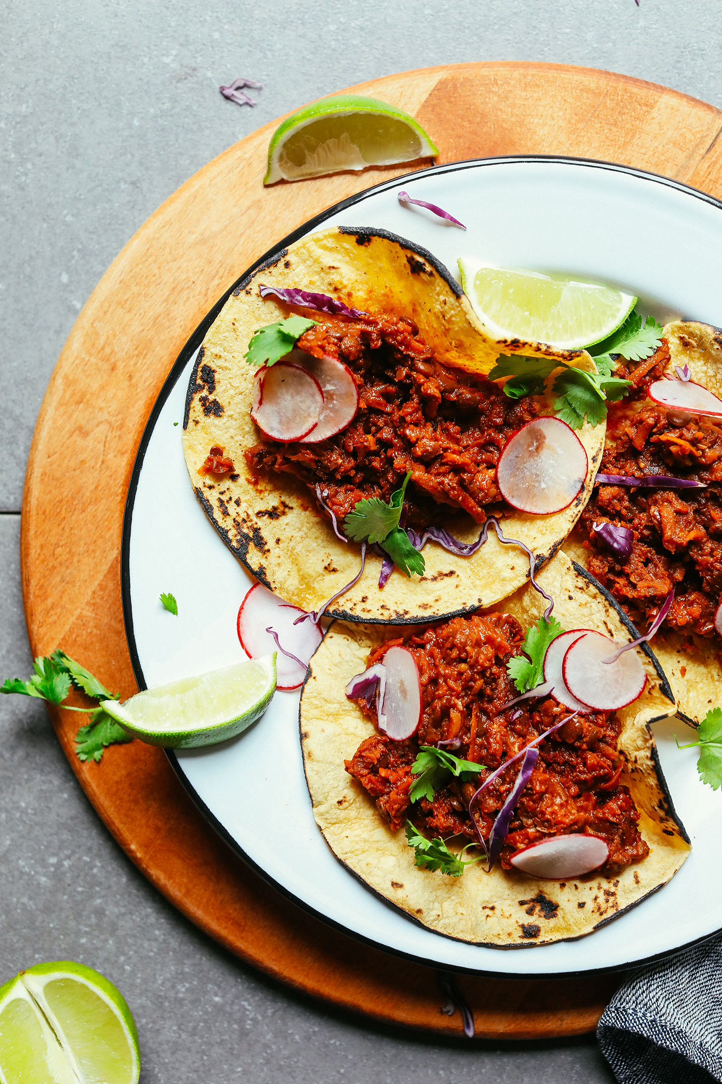 Dinner plate with three Vegan Barbacoa Tacos with sliced radishes, cilantro, and fresh limes