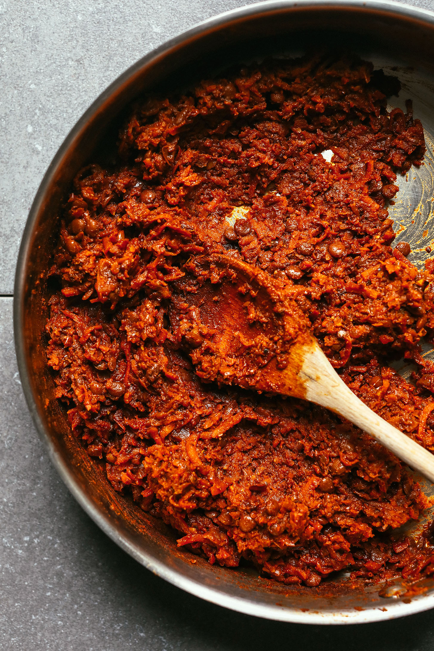 Using a wooden spoon to stir Vegan Barbacoa in a large skillet