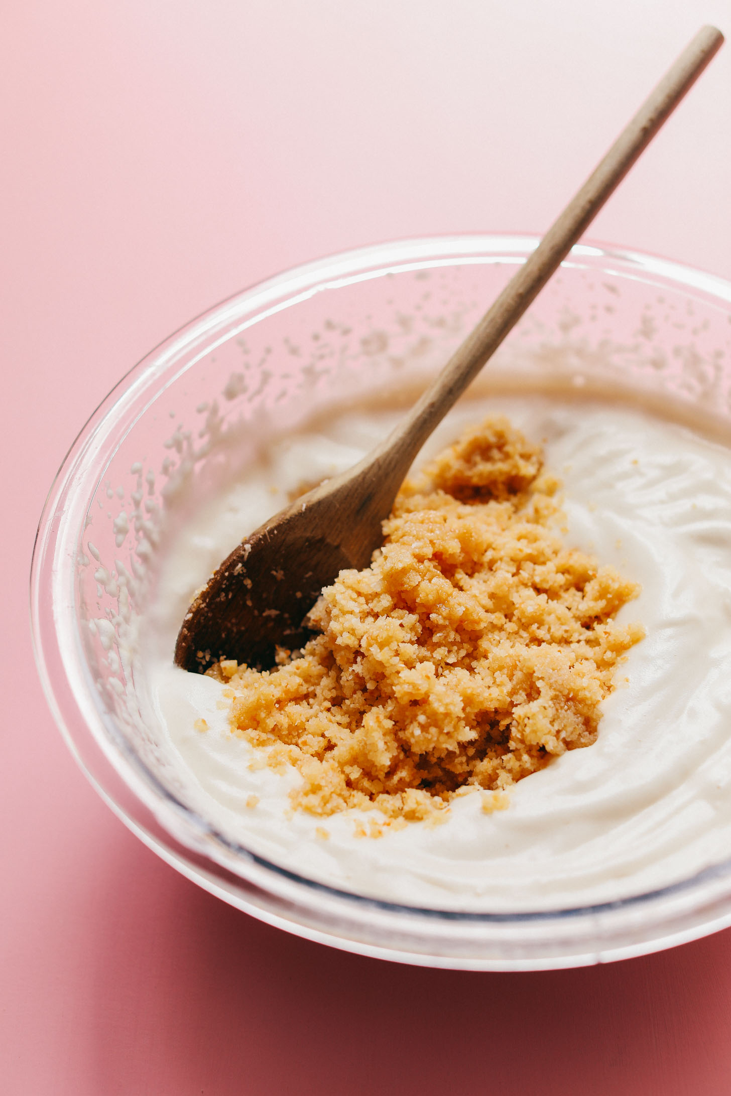 Using a wood spoon to stir chopped toasted coconut into aquafaba