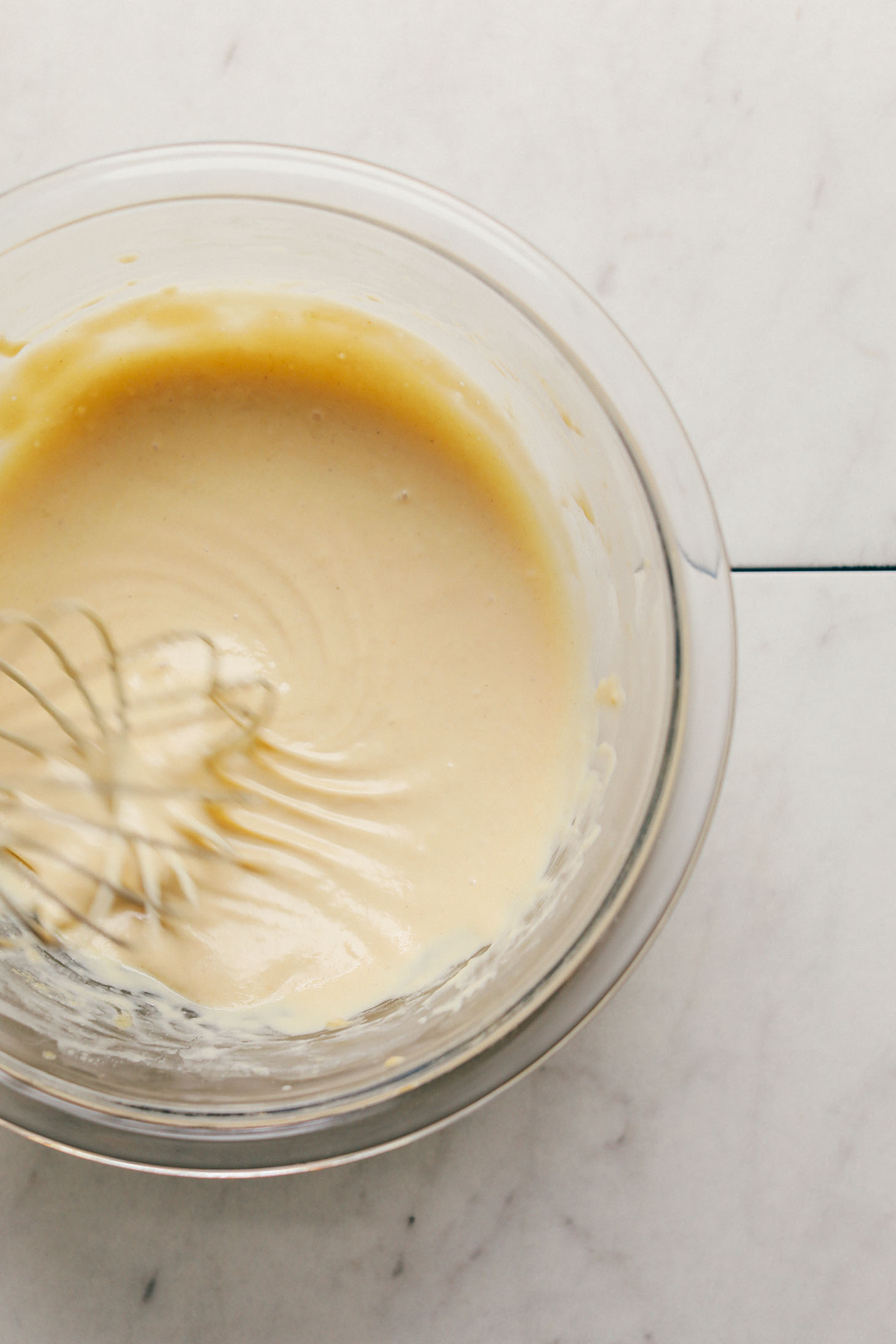 Whisking tahini dressing in a glass bowl