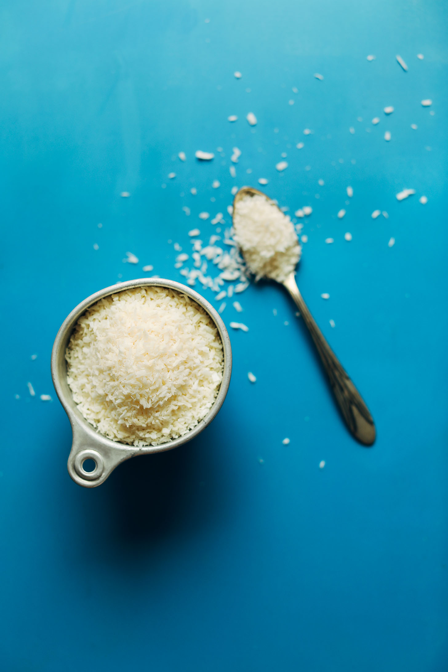 Measuring cup and spoon of shredded coconut for making homemade coconut butter