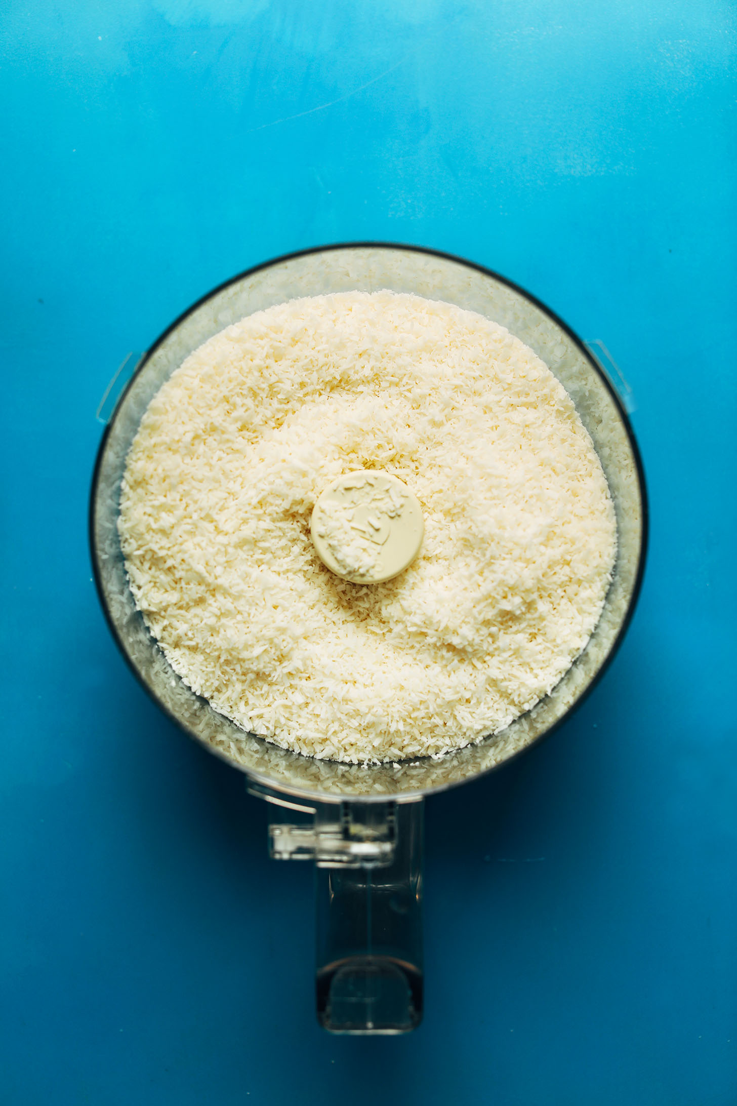 Food processor filled with shredded coconut for making homemade coconut butter