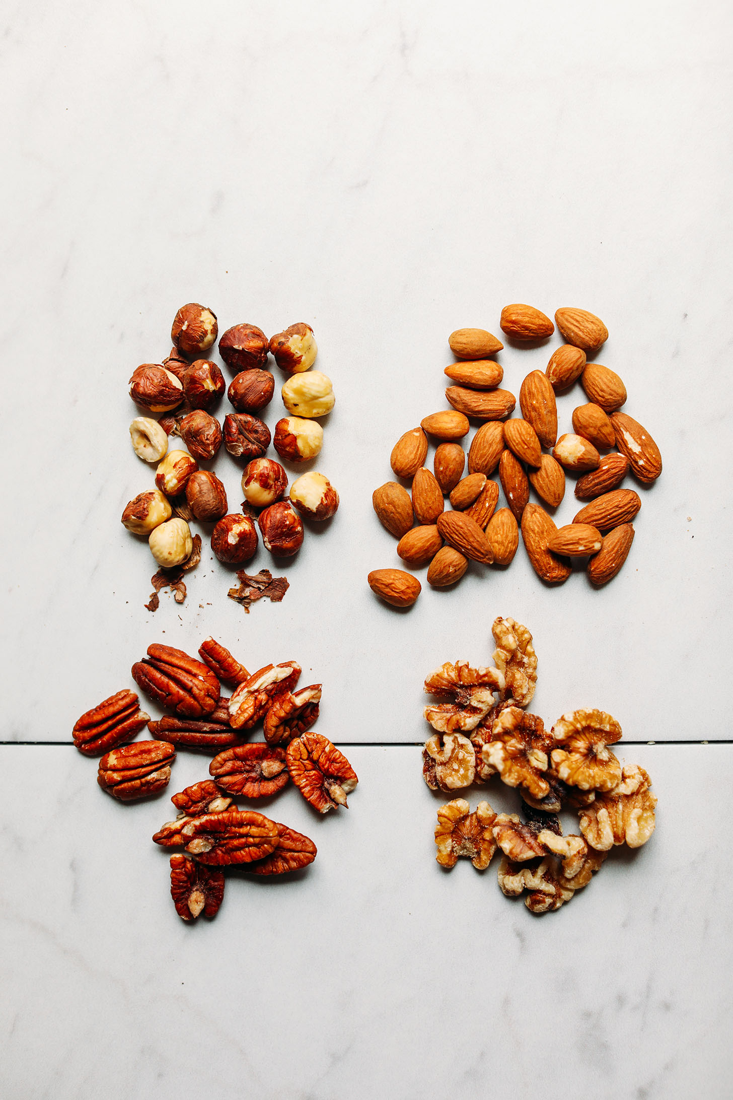 Walnuts, pecans, almonds, and hazelnuts on a marble background