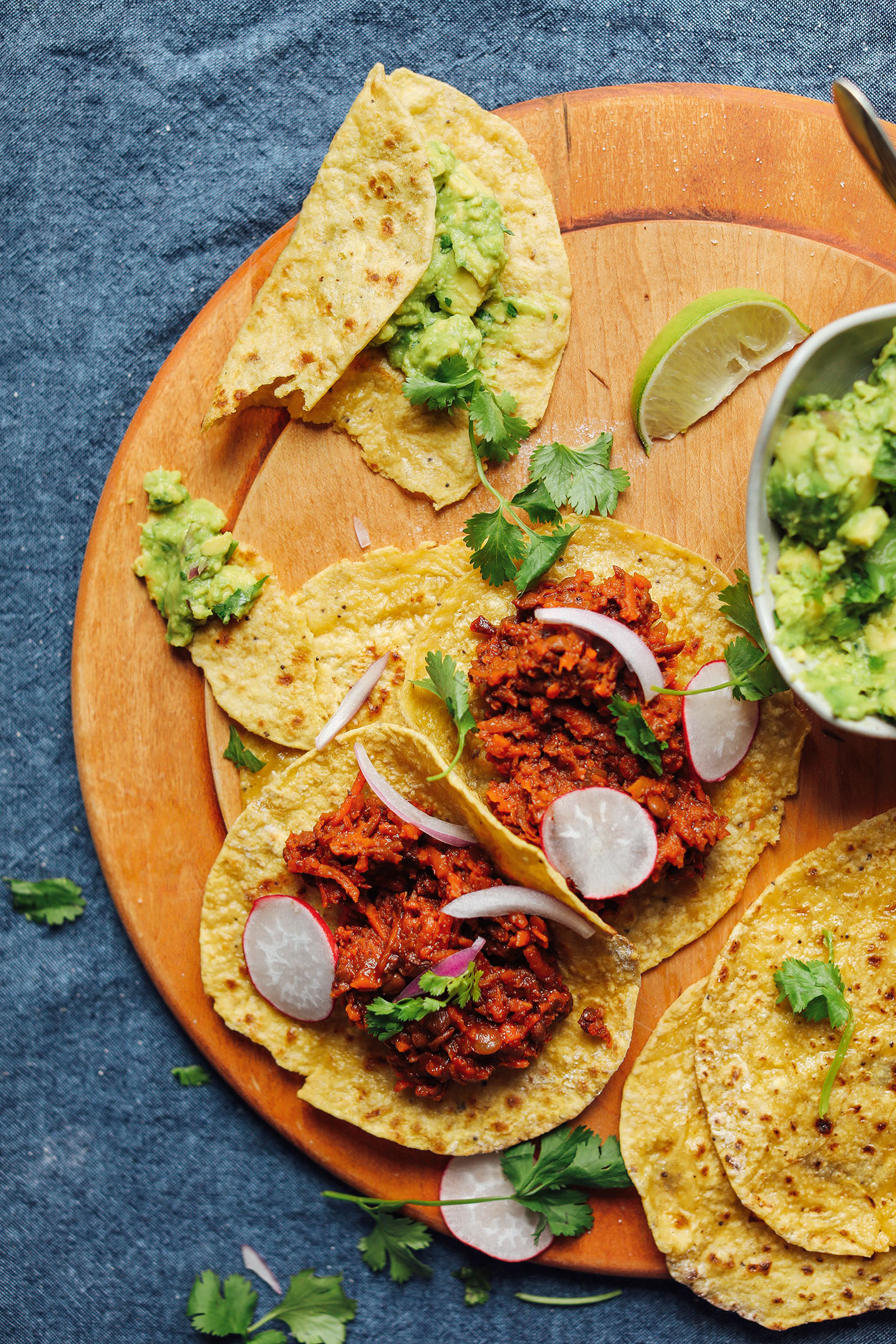 Cutting board with grain-free Plantain Tortillas filled with Barbacoa Lentils and guacamole