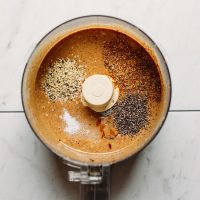 Food processor filled with ingredients for making our homemade nut butter recipe