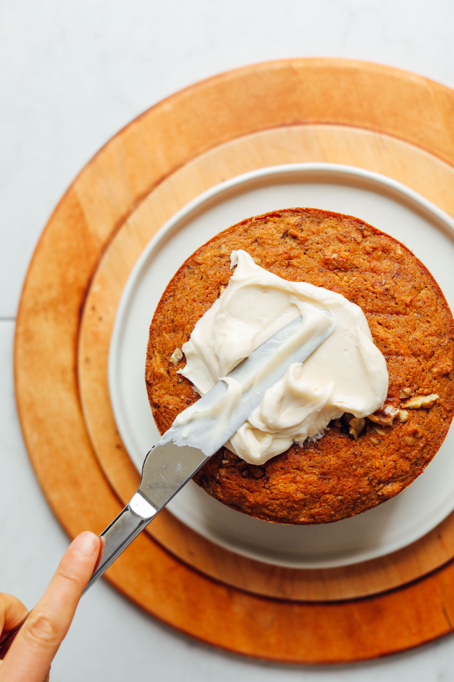 Spreading delicious vegan frosting onto Gluten-Free Vegan Carrot Cake