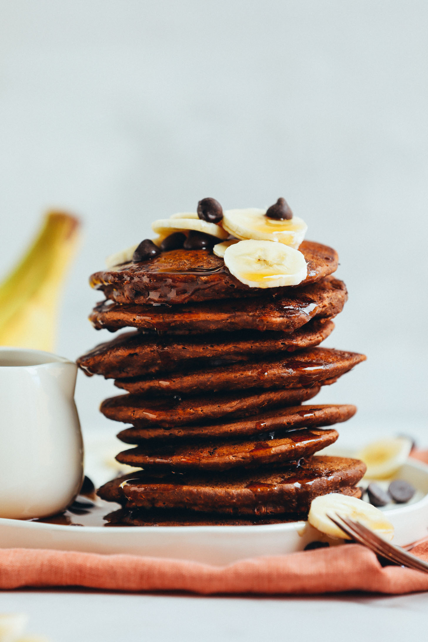 Stack of Amazing Vegan Chocolate Chocolate Chip Pancakes topped with fresh banana