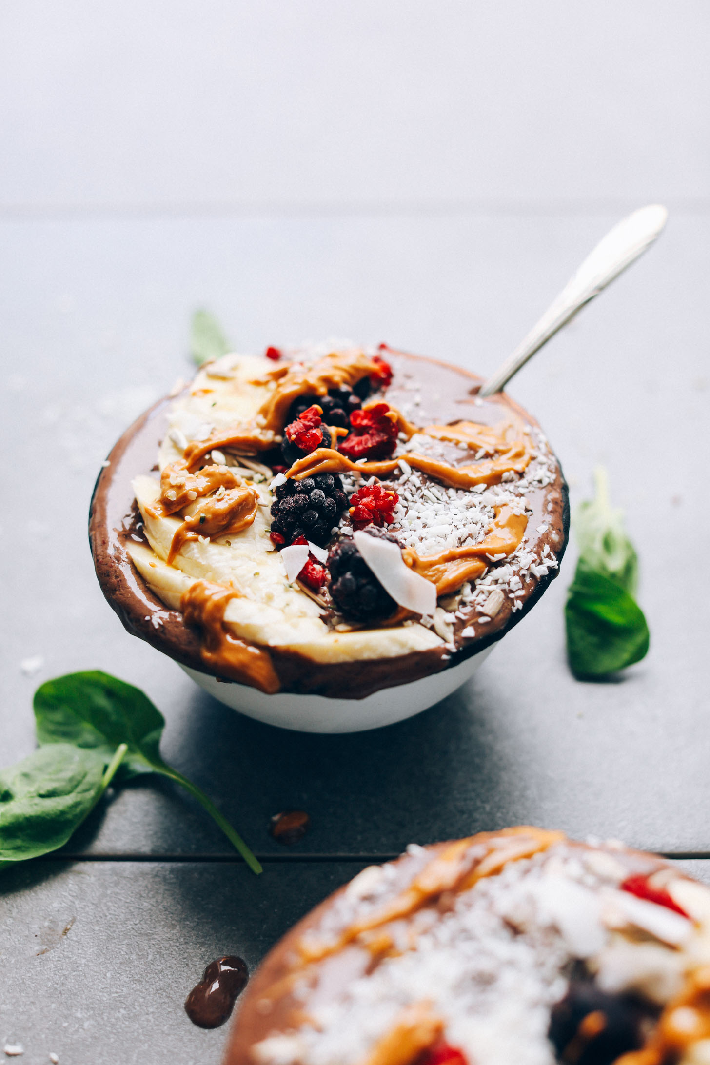 Close up shot of an overflowing Peanut Butter & Jelly Acai Bowl with fresh fruit, coconut, and nut butter