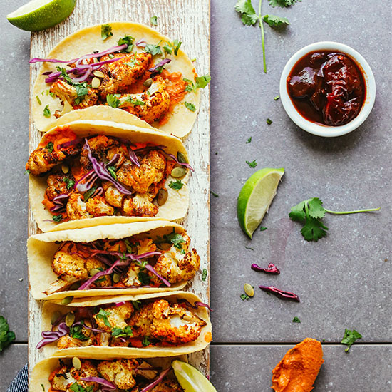 Wood board filled with Roasted Cauliflower Tacos made with Adobo Romesco