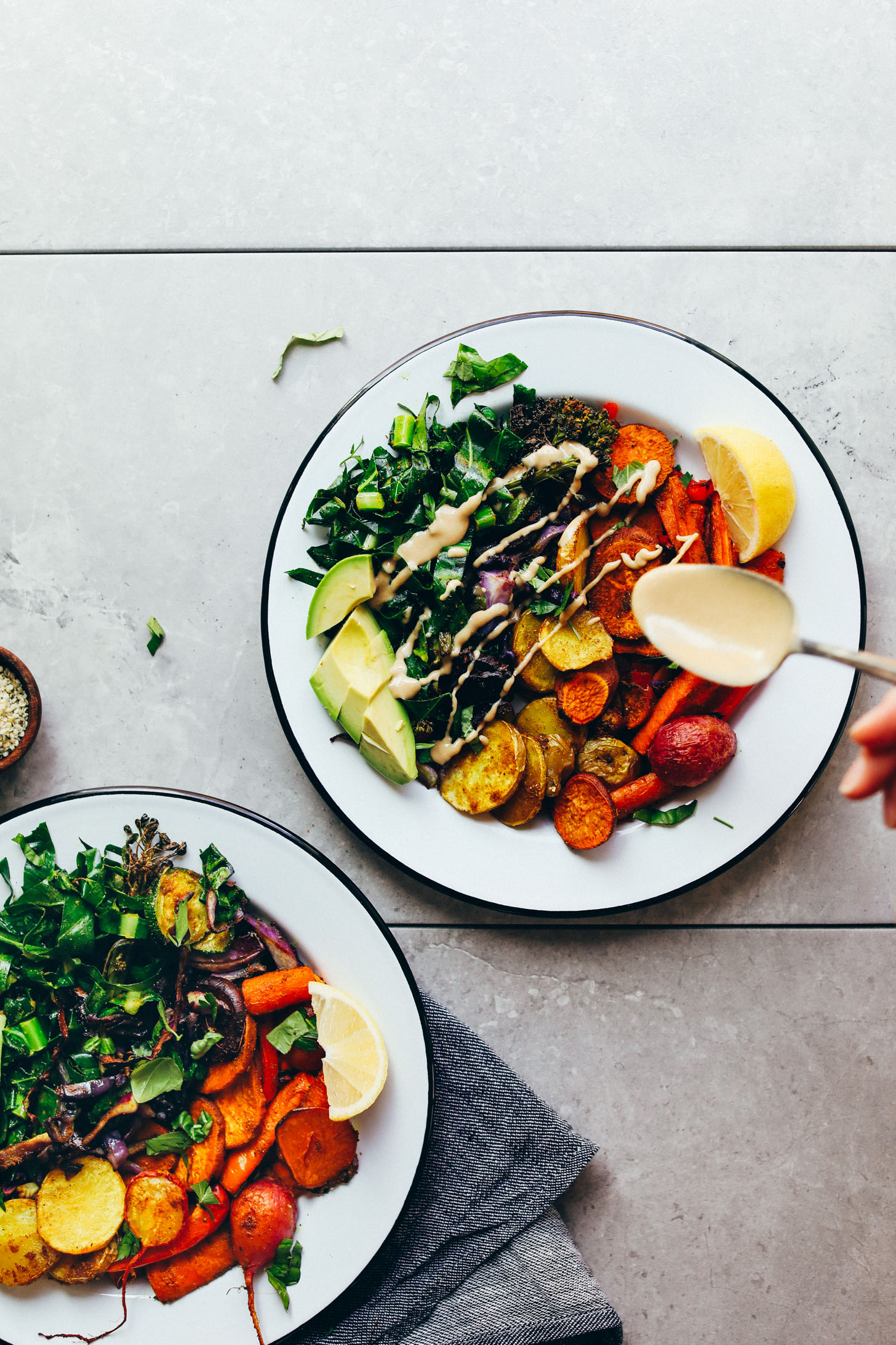 Drizzling tahini dressing onto a nourishing, delicious Roasted Rainbow Vegetable Bowl for a healthy plant-based meal