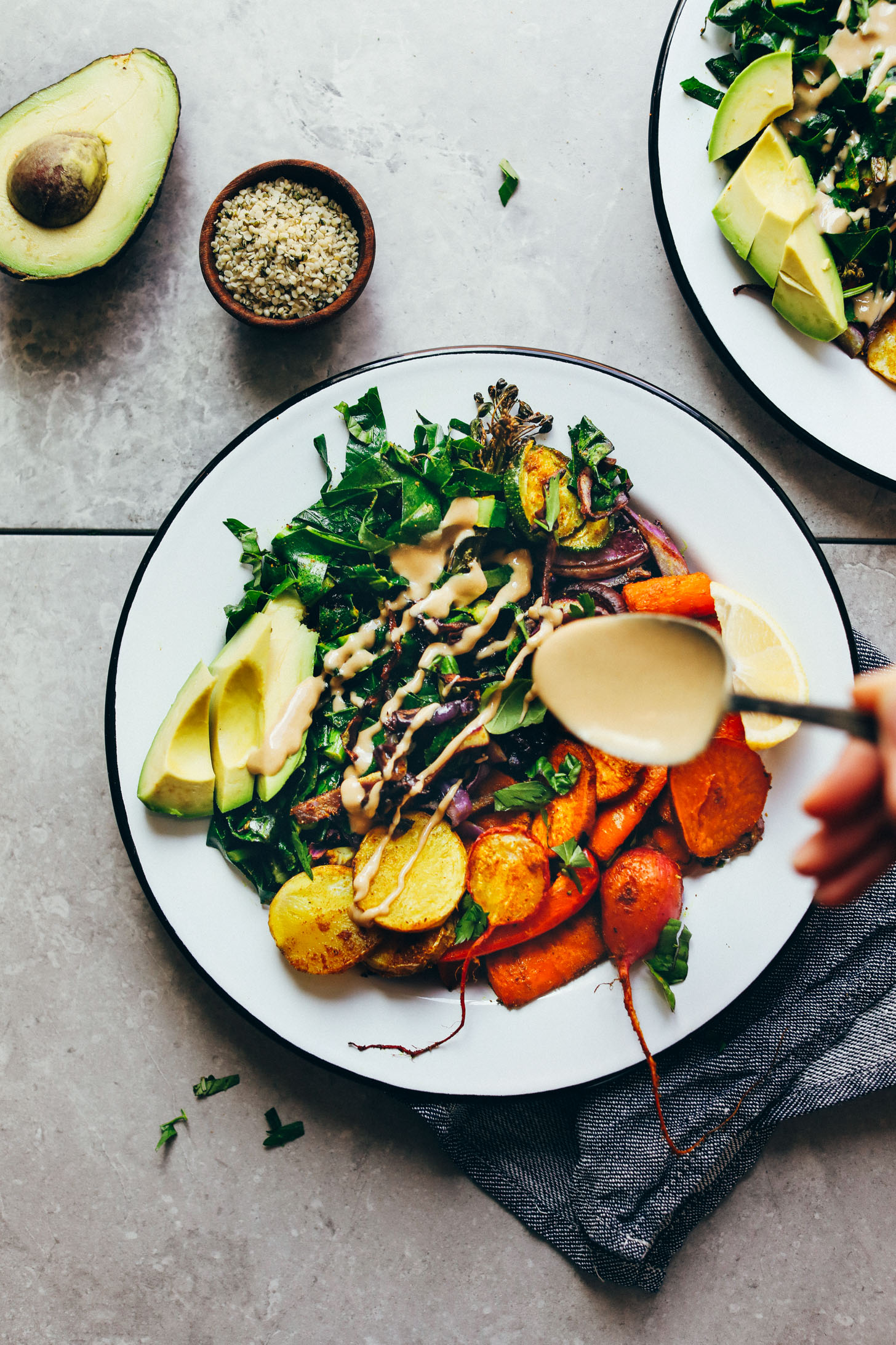 Drizzling tahini dressing onto our Rainbow Roasted Vegetable Bowl recipe