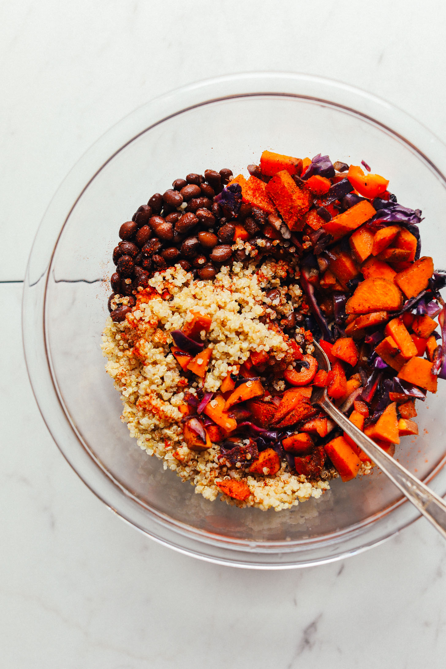 Mixing bowl with quinoa, black beans, sweet potatoes, cabbage, red bell pepper, and spices for filling portobello mushrooms