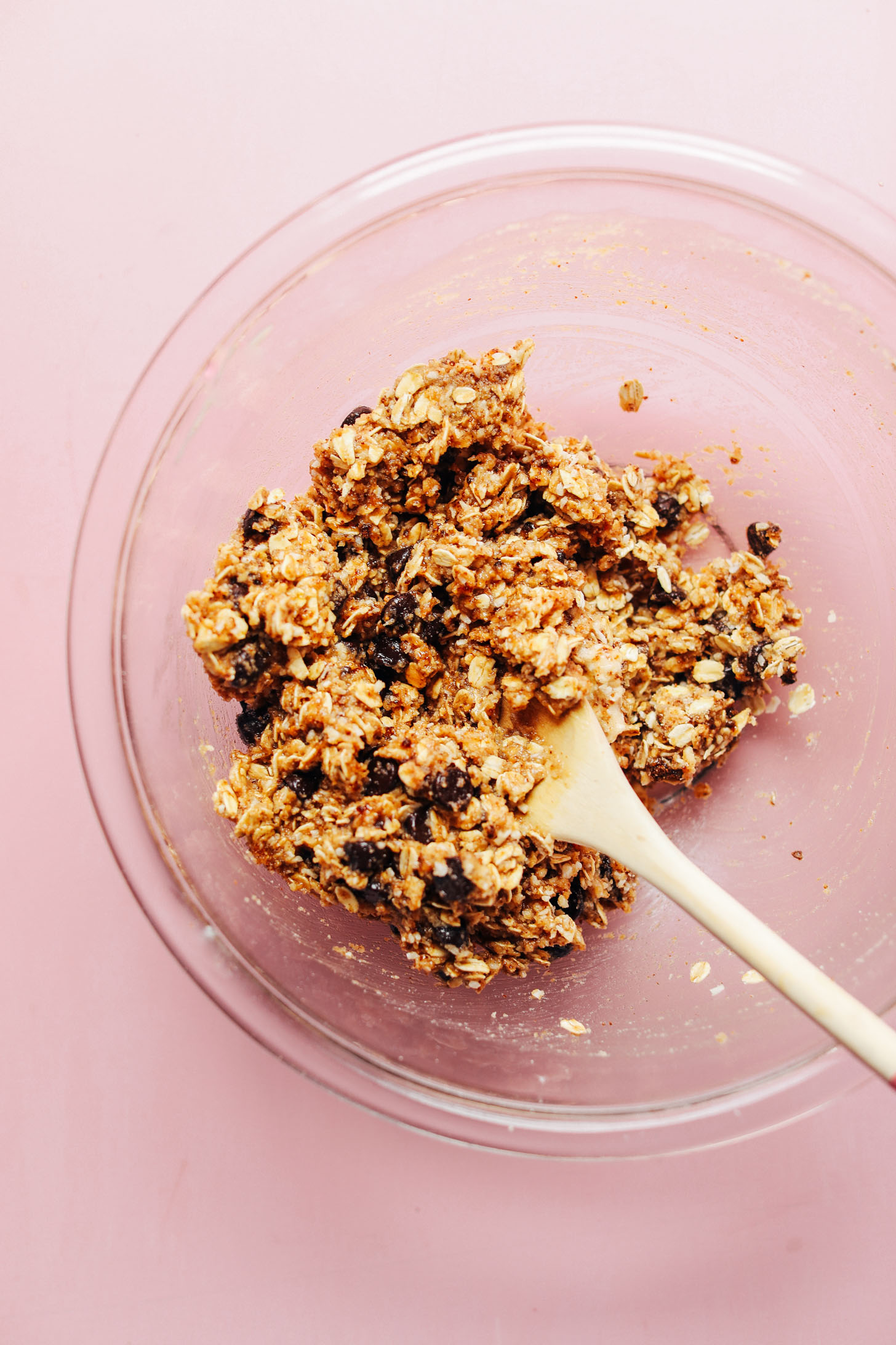 Using a wooden spoon to stir together ingredients for Healthy Gluten-Free Oatmeal Chocolate Chip Cookies