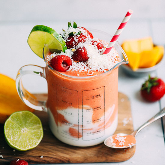 Glass serving jar with a swirl of coconut milk and our Mango Berry Smoothie recipe