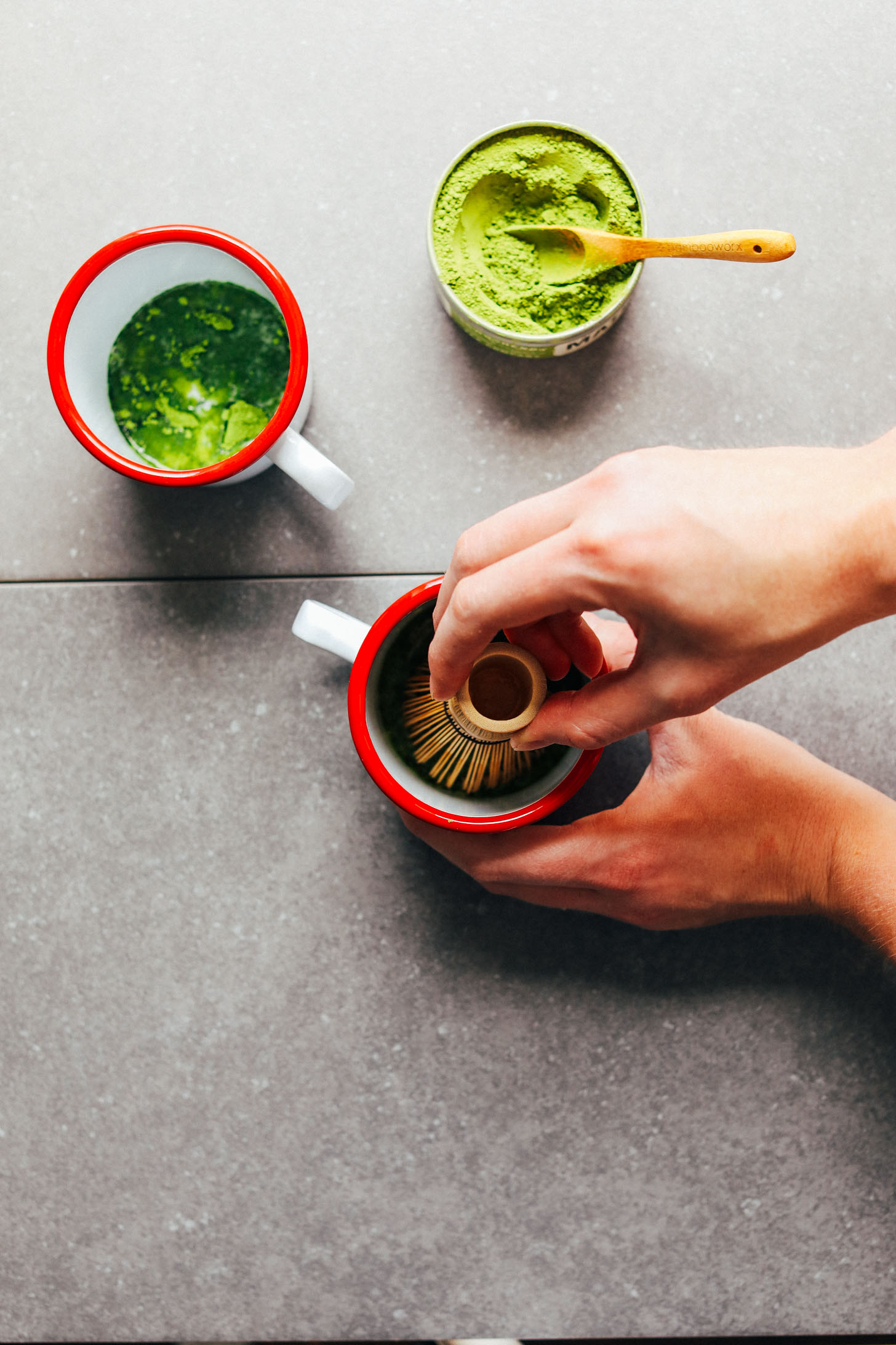 Using a bamboo whisk to stir together matcha, sweetener, and a bit of nut milk