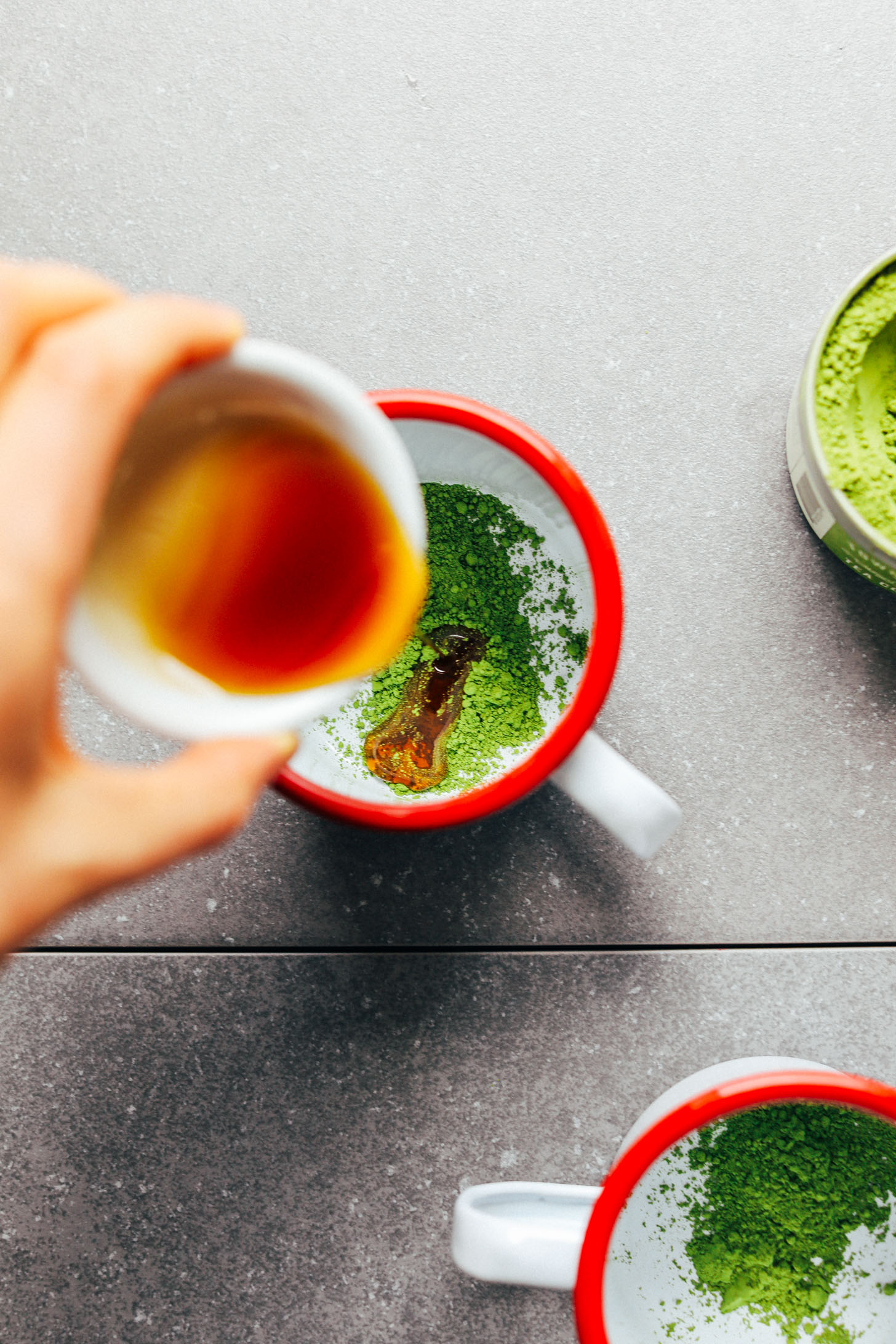 Pouring sweetener into a mug with matcha powder for making the best vegan matcha latte
