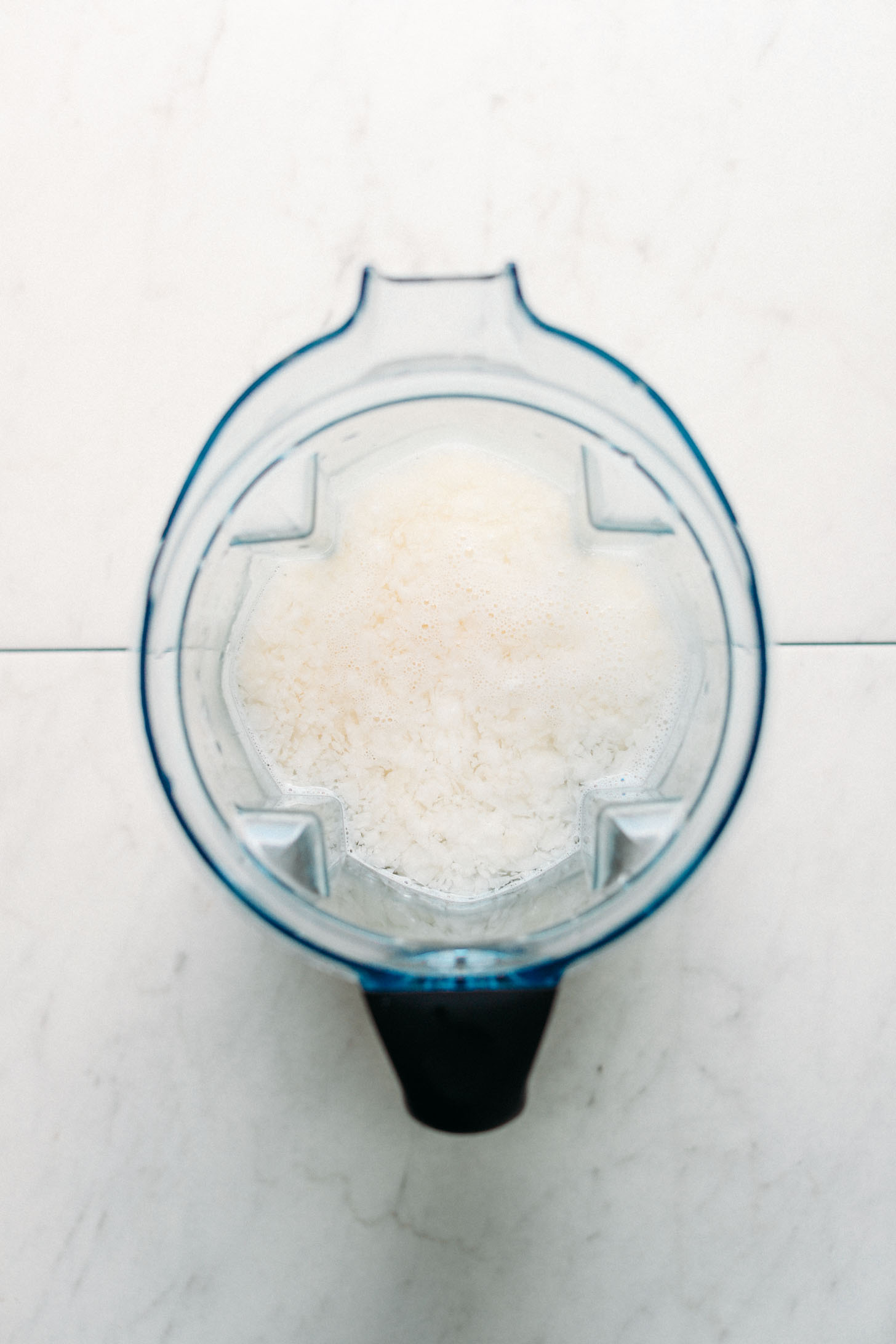 Blender filled with coconut and water for showing How To Make Coconut Milk