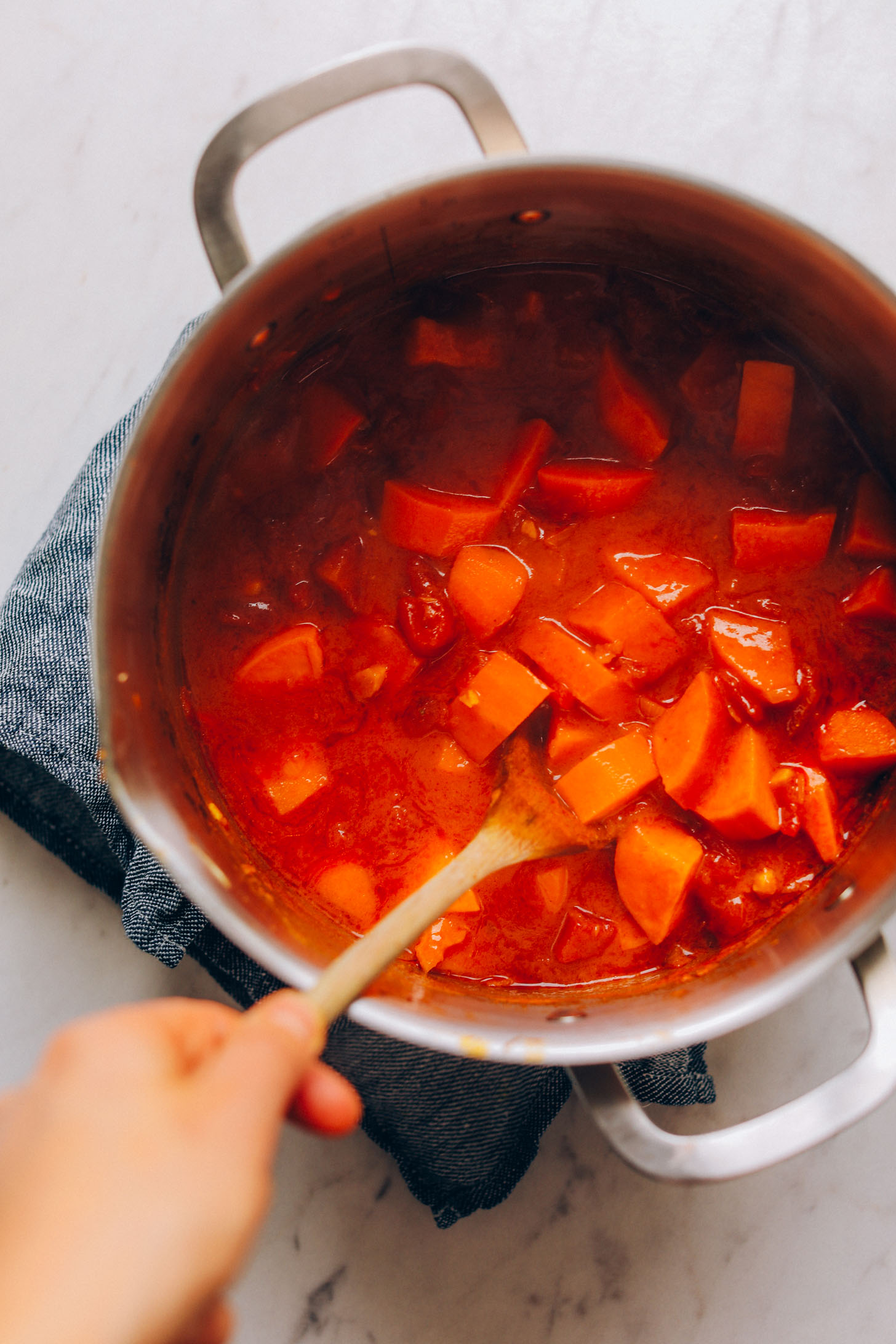Stirring together ingredients for vegan Sweet Potato Cauliflower Curry