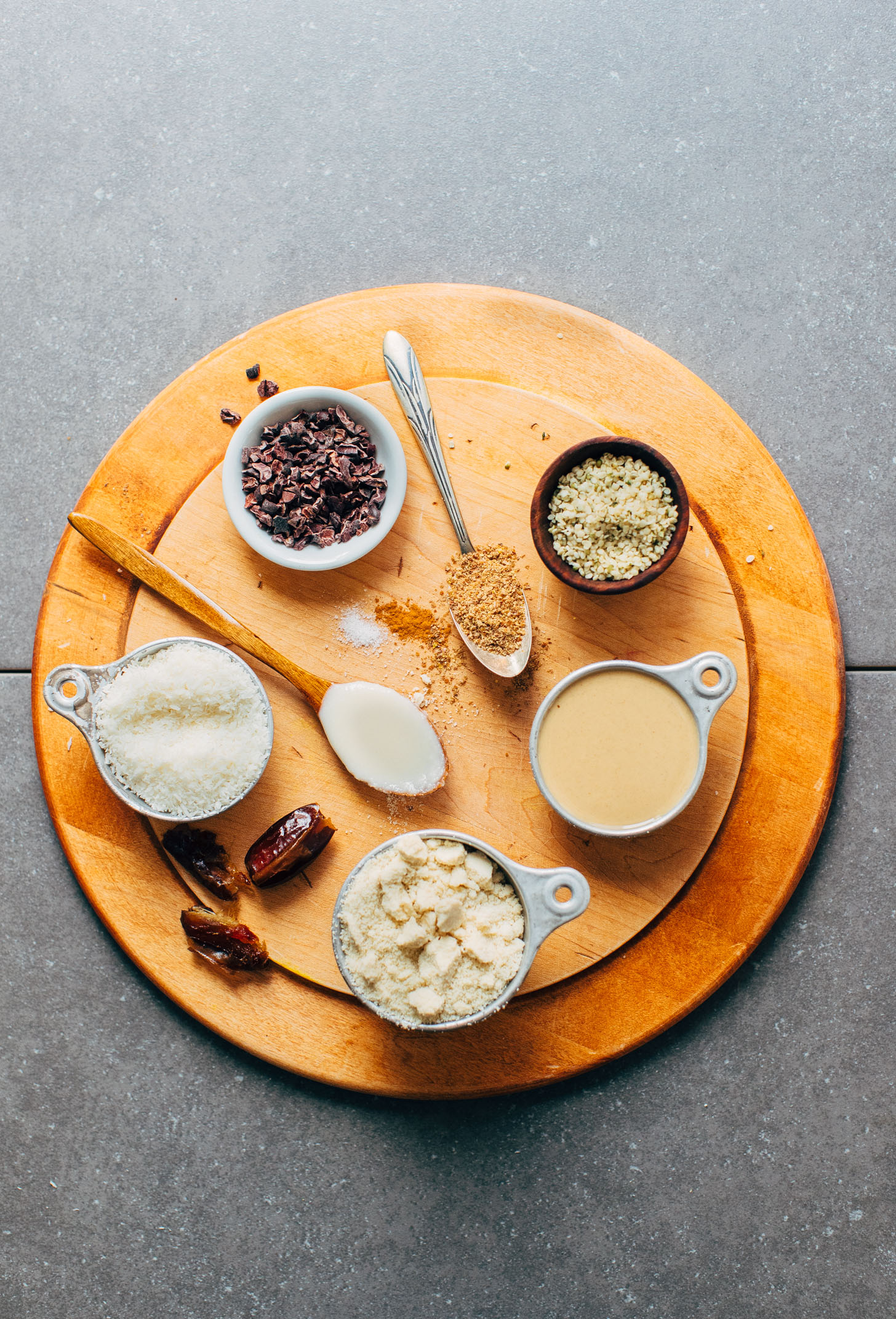 Wooden cutting board with ingredients for making gluten-free vegan Coconut Cacao Tahini Snack Bites
