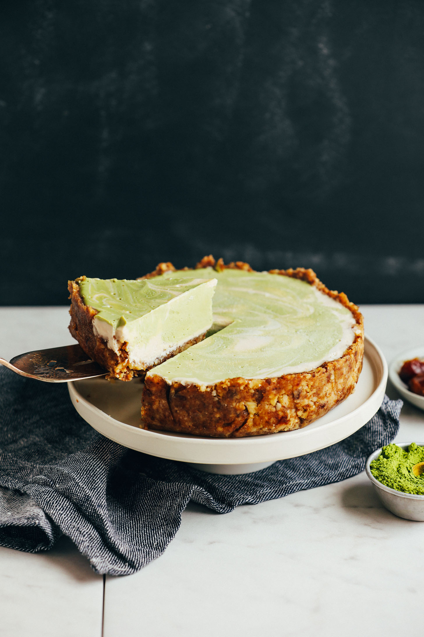 Picking up a slice of chilled gluten-free vegan Matcha Swirl Cheesecake