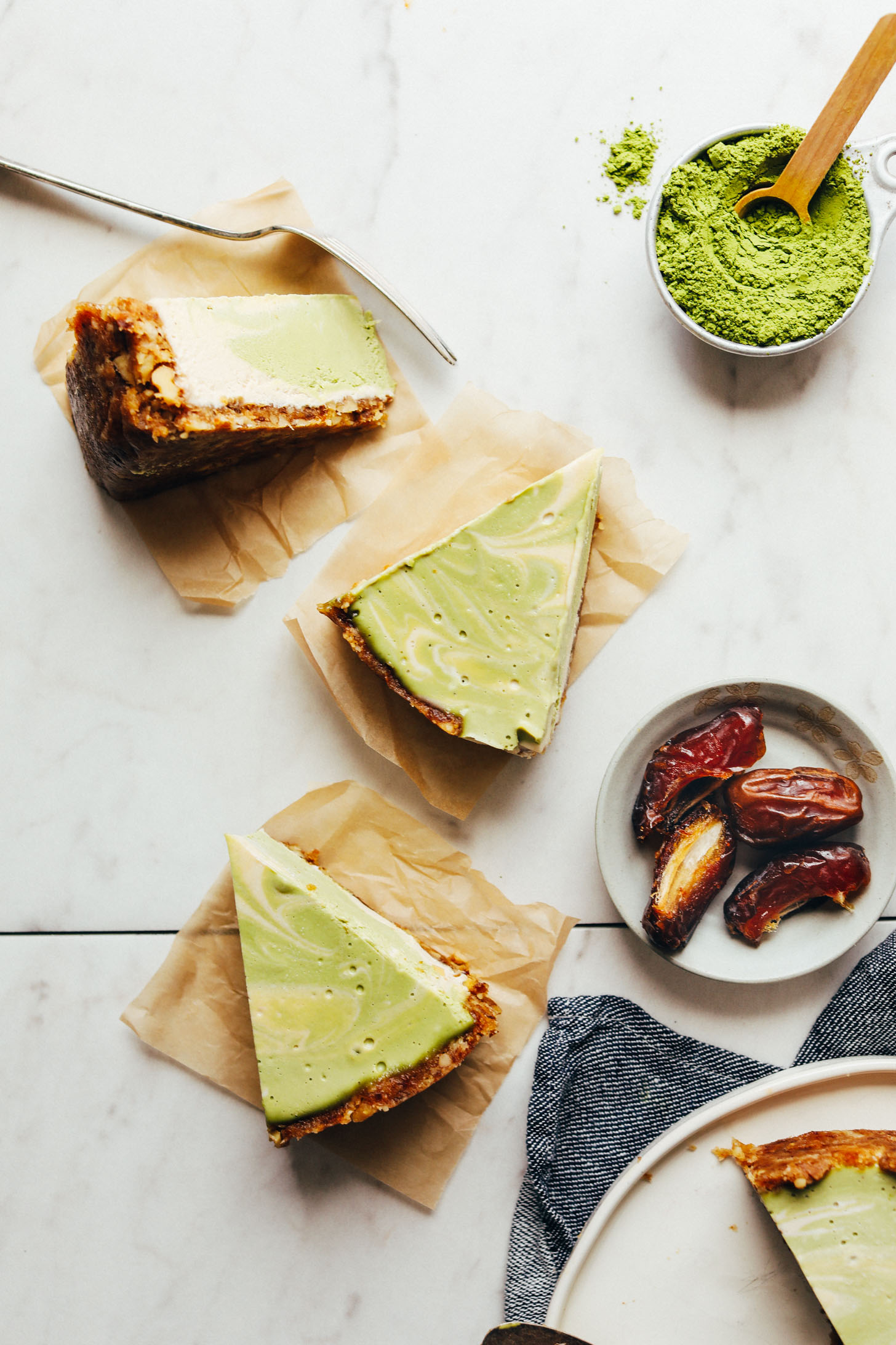 Slices of gluten-free vegan Matcha Swirl Cheesecake on squares of parchment paper