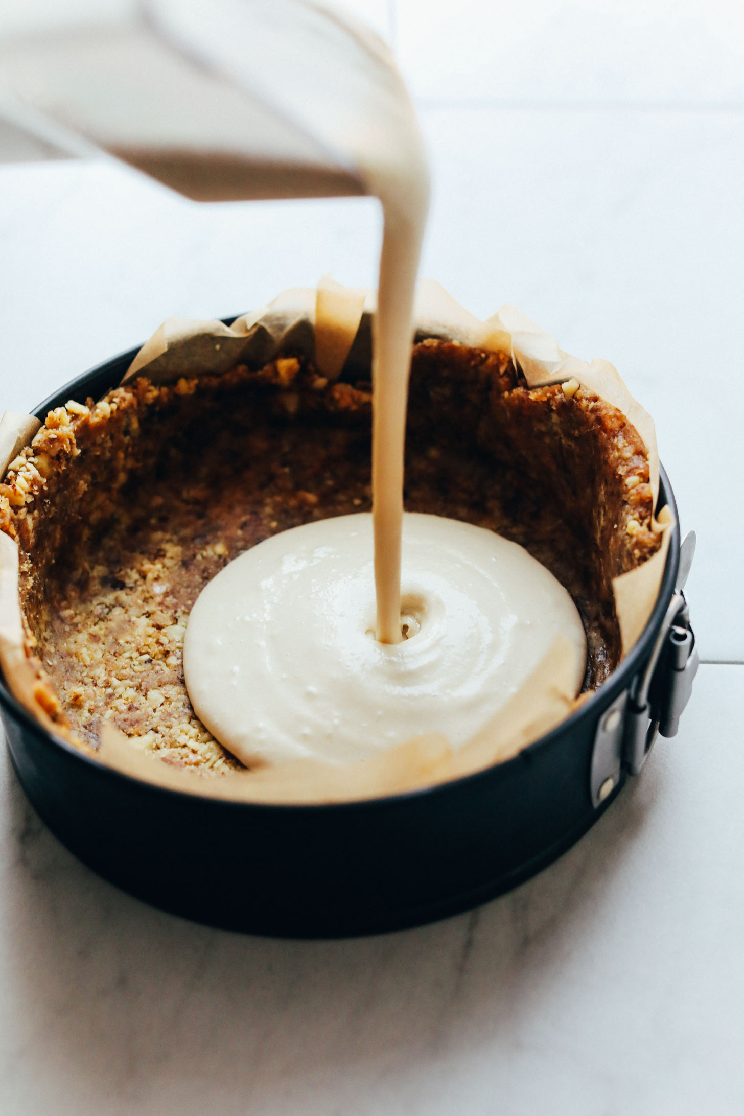 Pouring filling into crust for vegan Matcha Swirl Cheesecake