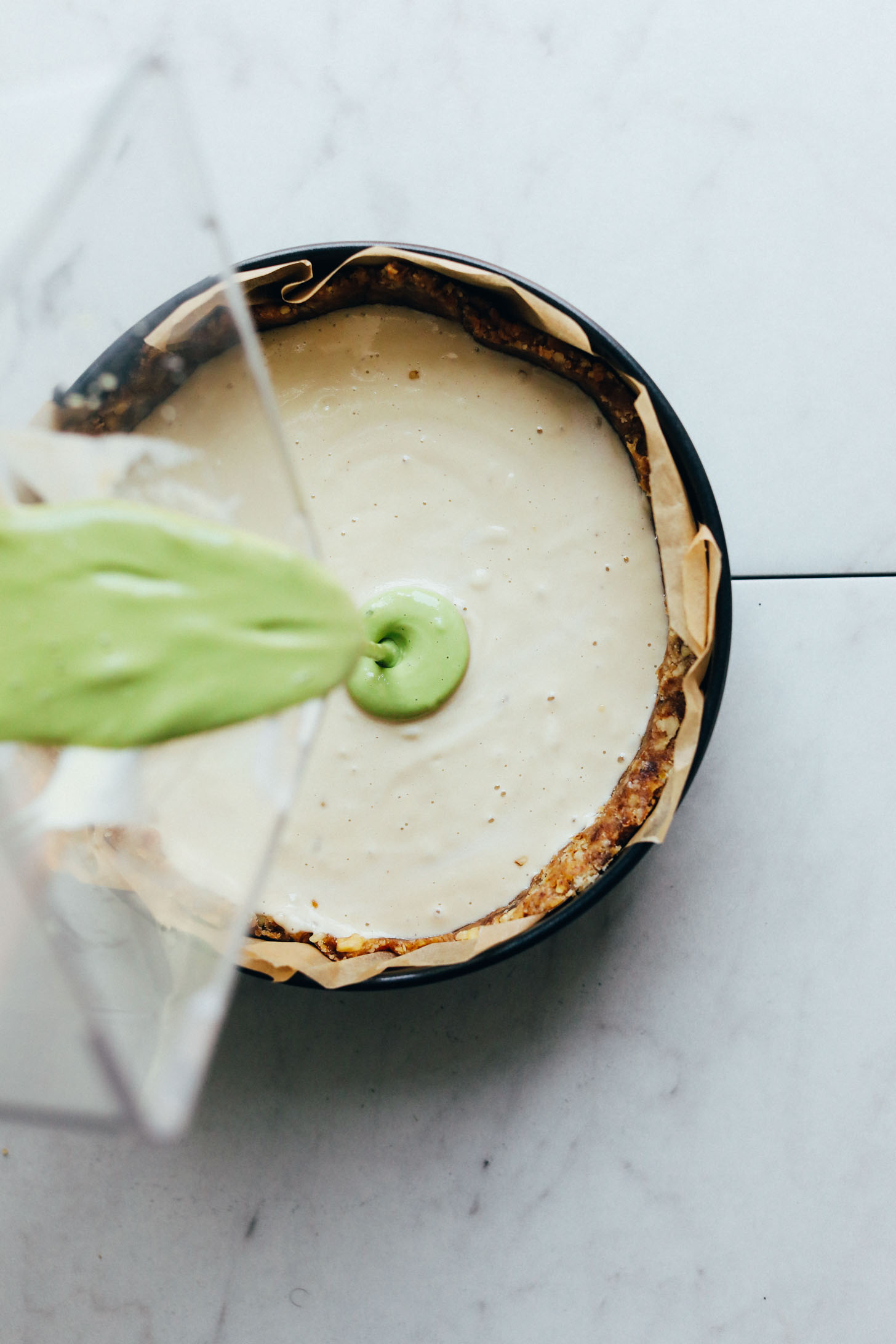 Pouring green matcha filling over white filling to create a swirl