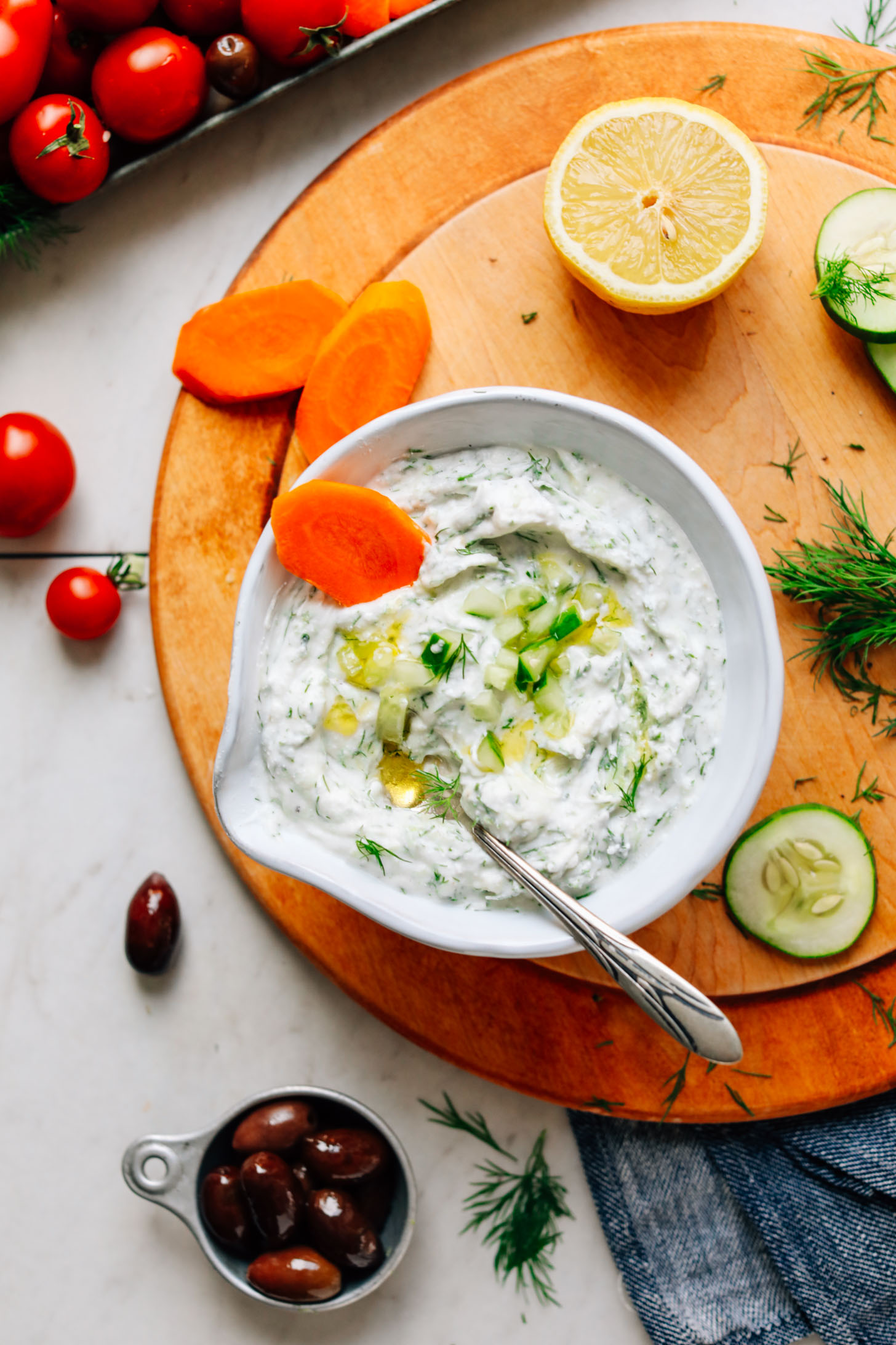 Bowl of flavorful Vegan Tzatziki on a wood cutting board