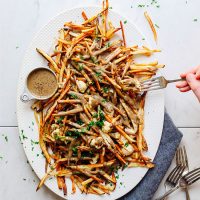 Using a fork to pick up a bite of Vegan Poutine made with mushroom gravy