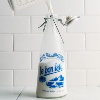 Pouring homemade coconut milk into an old-fashioned milk jug