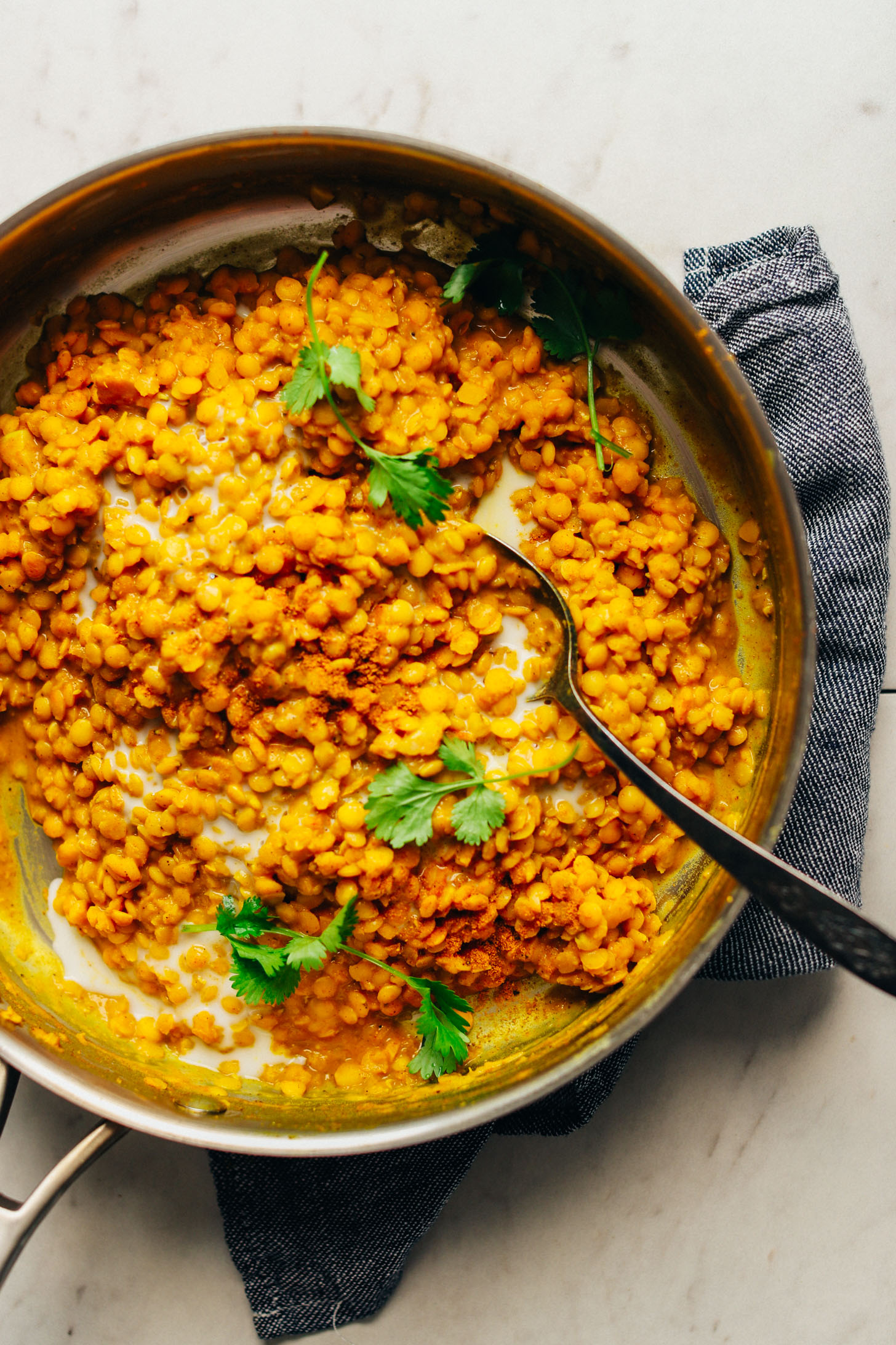 Stirring curried lentils in a large pan for our Curried Lentil Sweet Potato Bowls