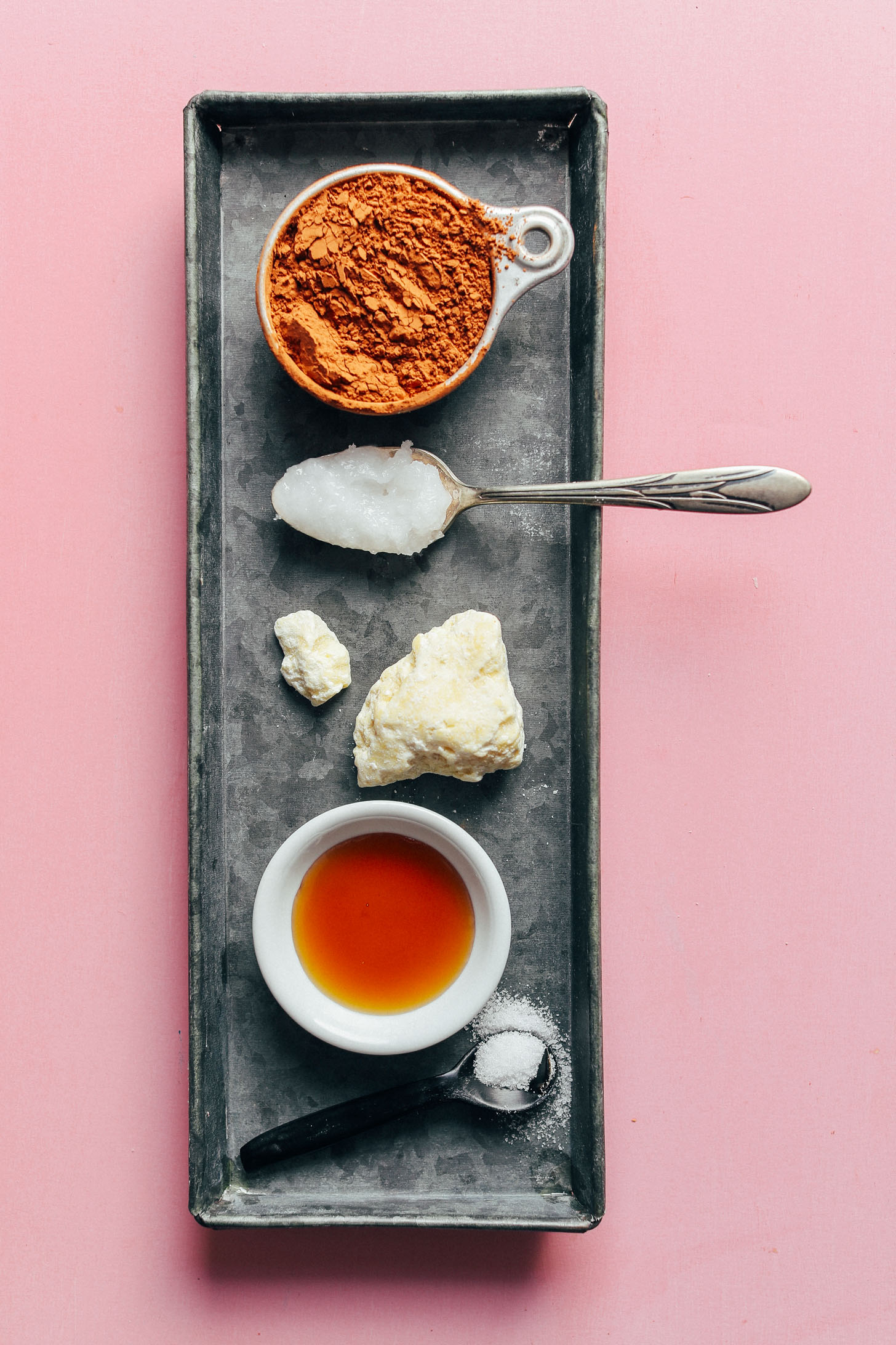 Metal serving platter showcasing cocoa powder, coconut oil, cacao butter, maple syrup and salt for vegan Coconut Butter Cups