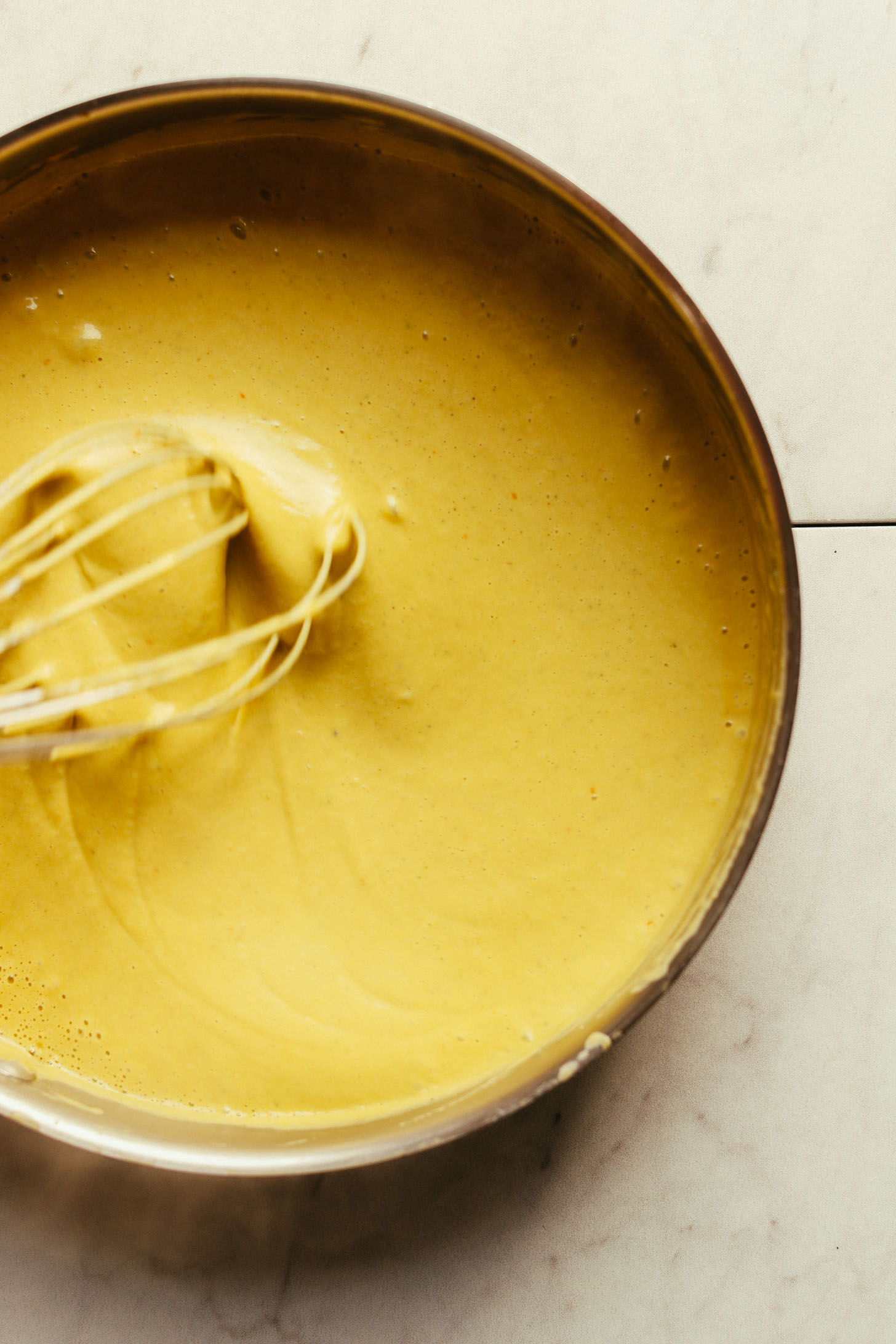 Whisking the sauce for gluten-free vegan Mac 'n' Cheese in a large saute pan