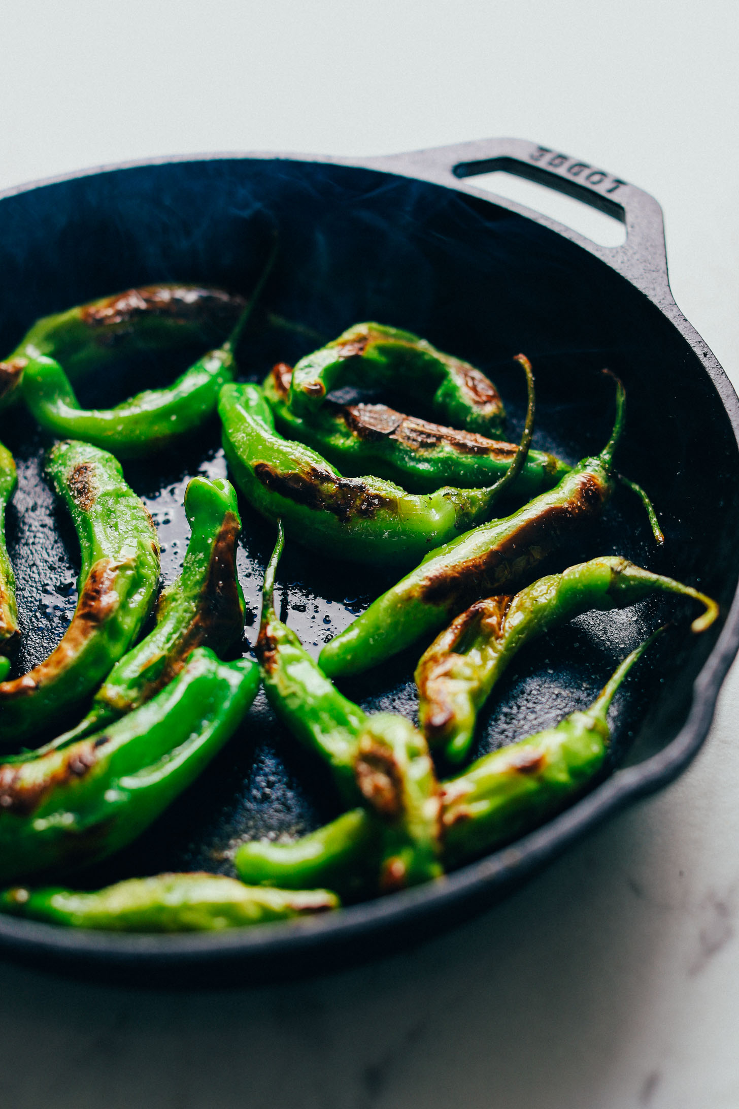 Pan roasting shishito peppers in a cast iron skillet