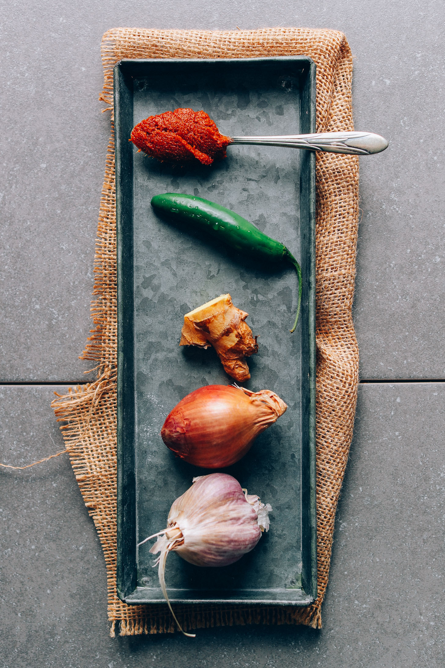Metal tray with tomato paste, serrano, ginger, shallot and garlic for seasoning our AMAZING Yellow Pumpkin Curry recipe