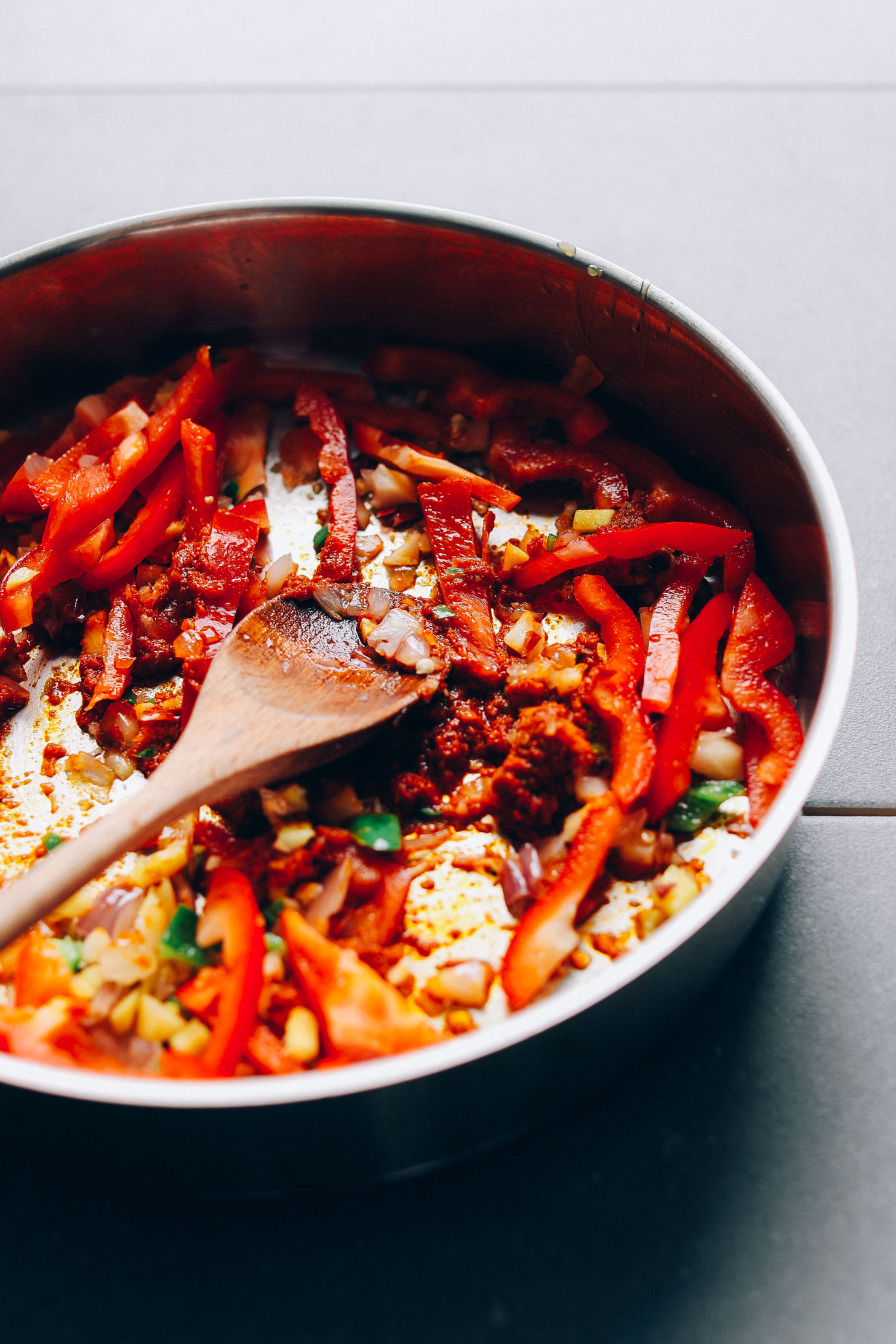 Stirring shallot, peppers, ginger, and tomato paste for vegan Yellow Pumpkin Curry