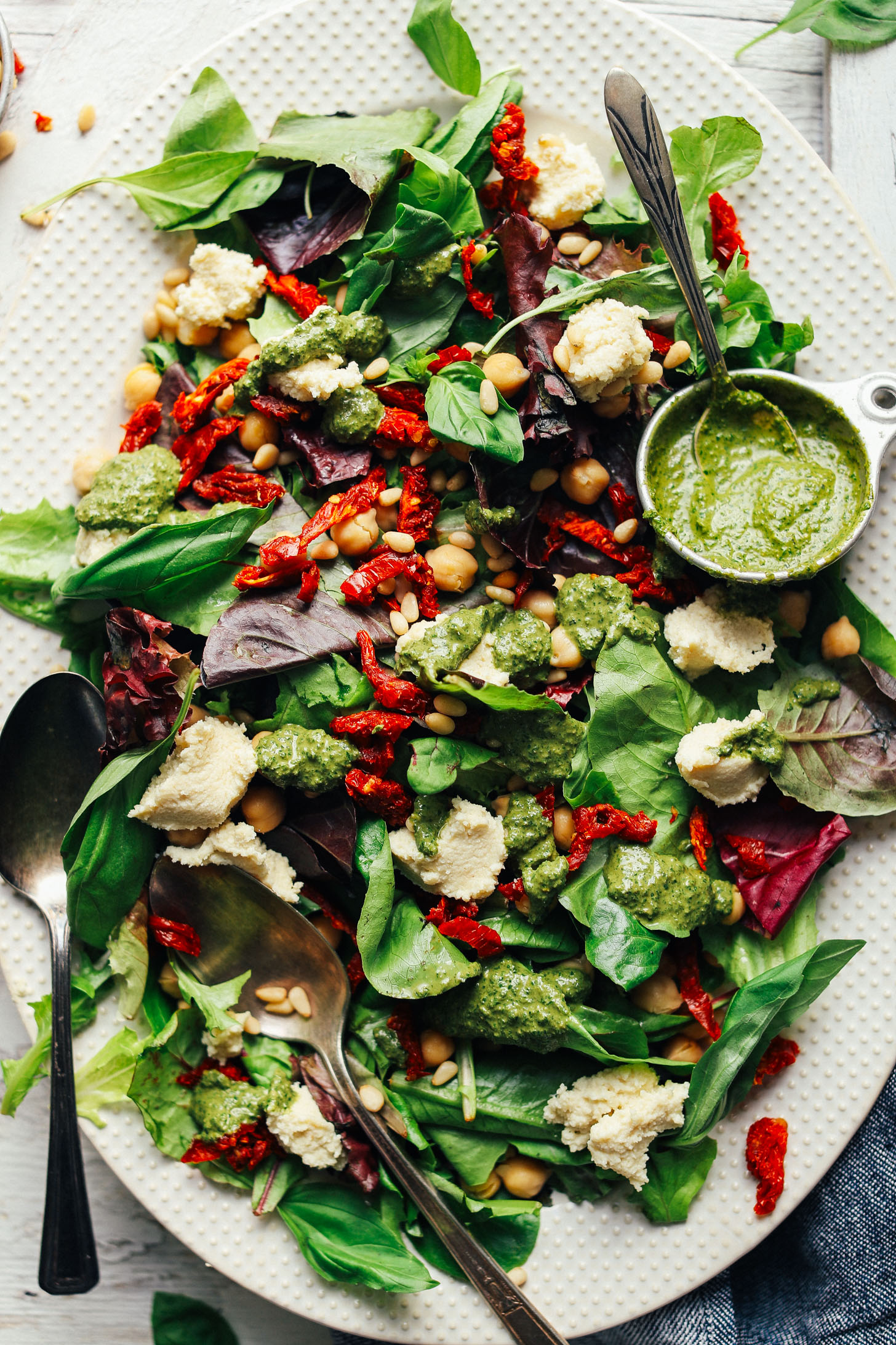 Close up shot showing our delicious vegan Green Salad with Almond Ricotta, Vibrant Pesto, and Sun-Dried Tomatoes