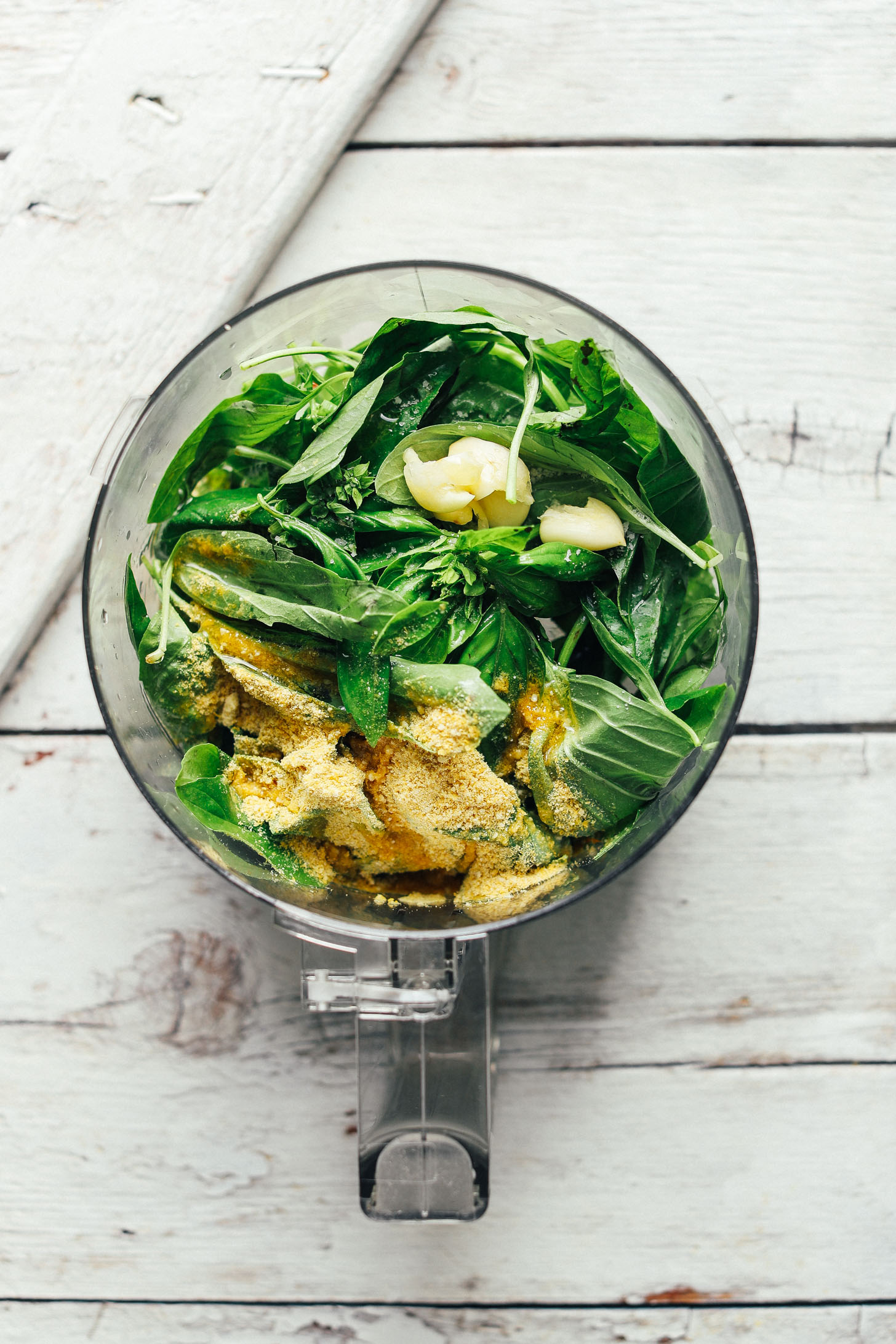 Food processor with pesto ingredients for our Green Salad with Almond Ricotta, Vibrant Pesto, and Sun-Dried Tomatoes
