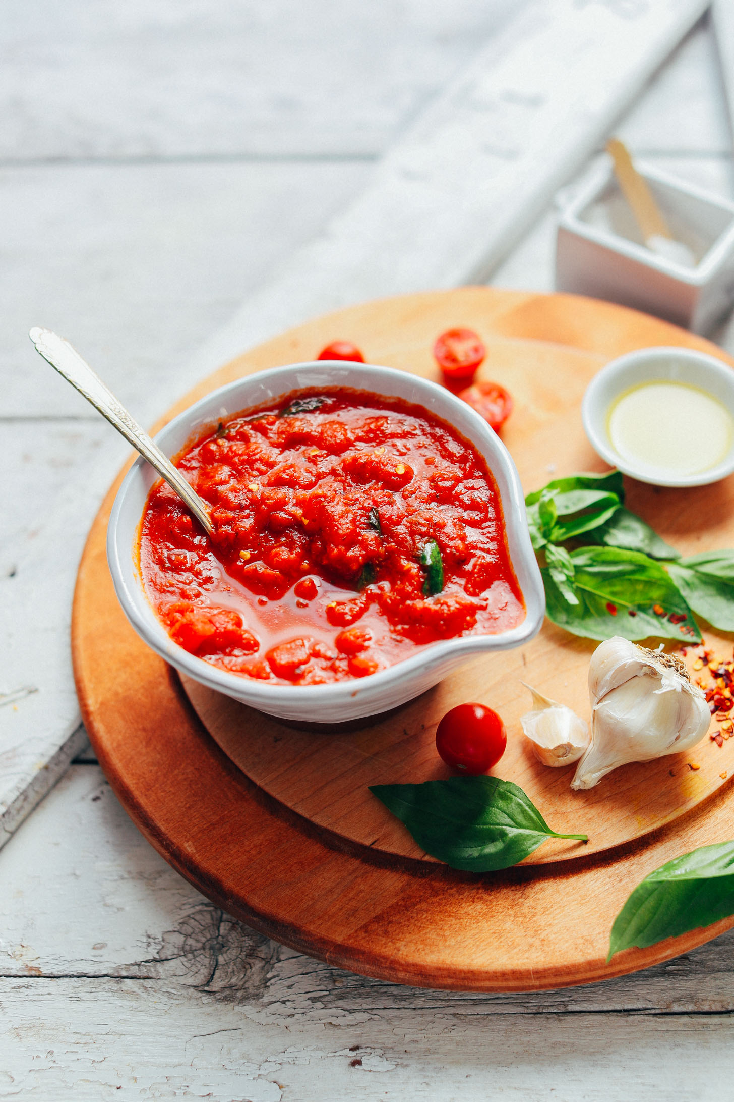Bowl of our gluten-free and vegan marinara sauce recipe on a cutting board with fresh ingredients