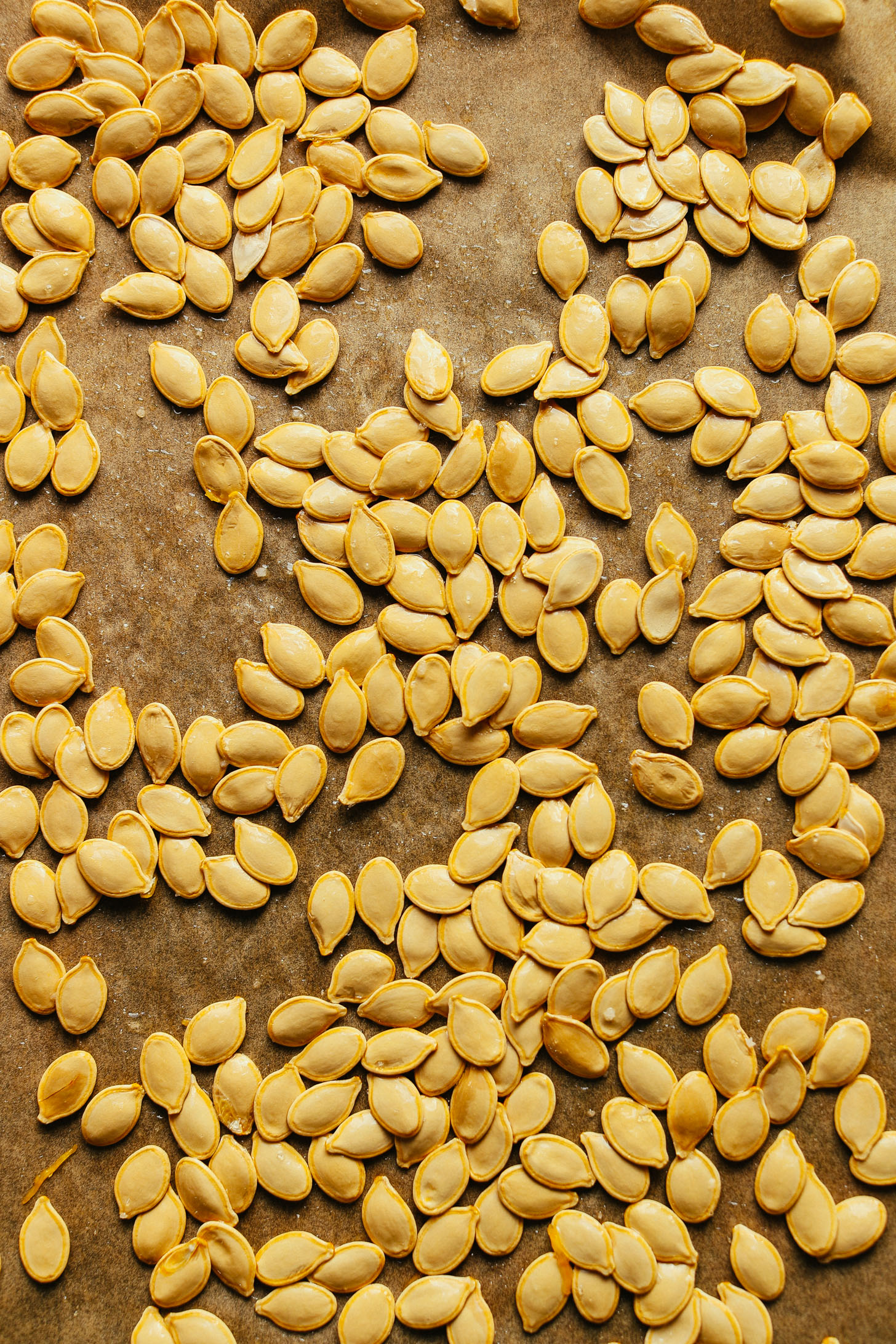 Parchment-lined baking sheet with pumpkin seeds for making Roasted Pumpkin Seeds