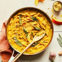 Pan of Vegan Pumpkin Mac 'n' Cheese topped with fresh sage leaves