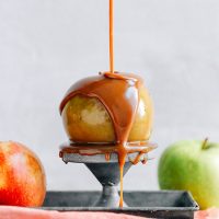 Drizzling Vegan Caramel Sauce onto an apple perched on a metal stand