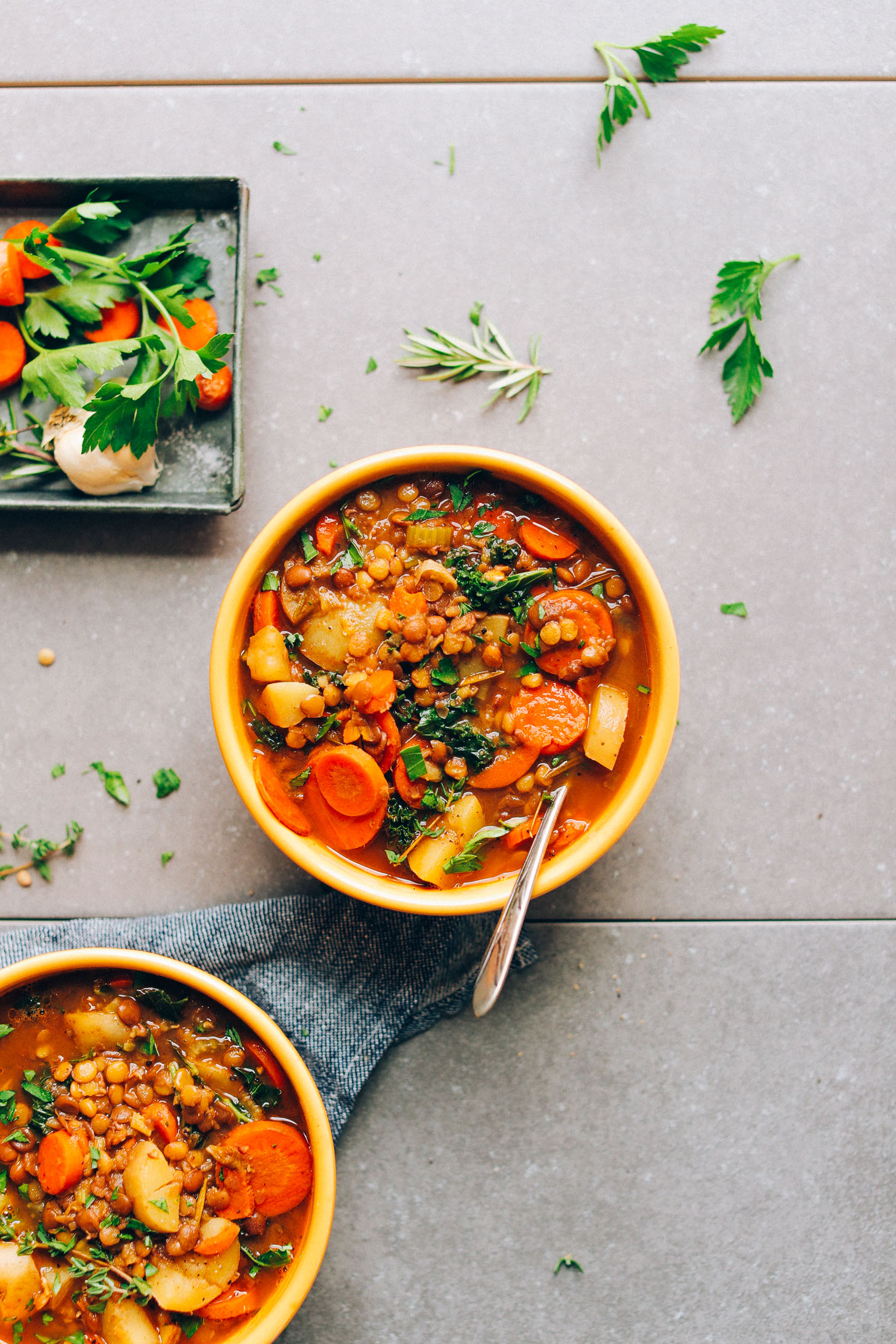 Overhead shot of two bowls of Everyday Lentil Soup with fresh herbs