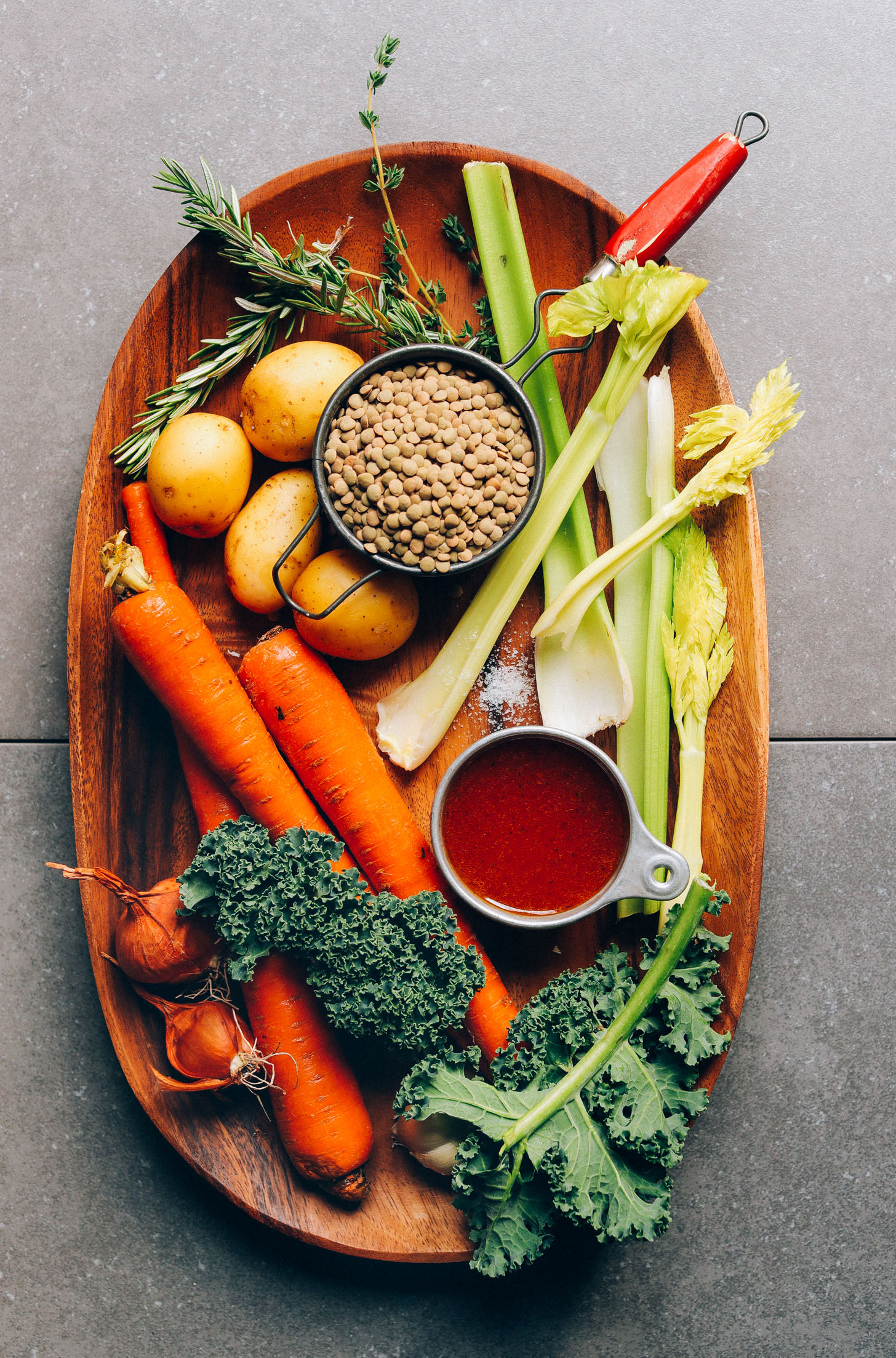 Wood platter with potatoes, rosemary, lentils, celery, broth, kale, carrots, and shallots