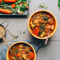 Bowls of Everyday Vegan Lentil Soup beside a tray of vegetables