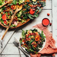 Plate and wood platter filled with Herbed Green Salad with Cranberry Dressing