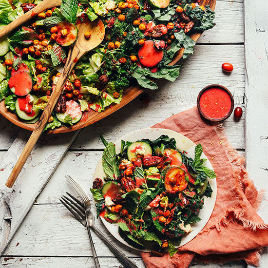 Plate and wood platter filled with Herbed Green Salad with Cranberry Dressing