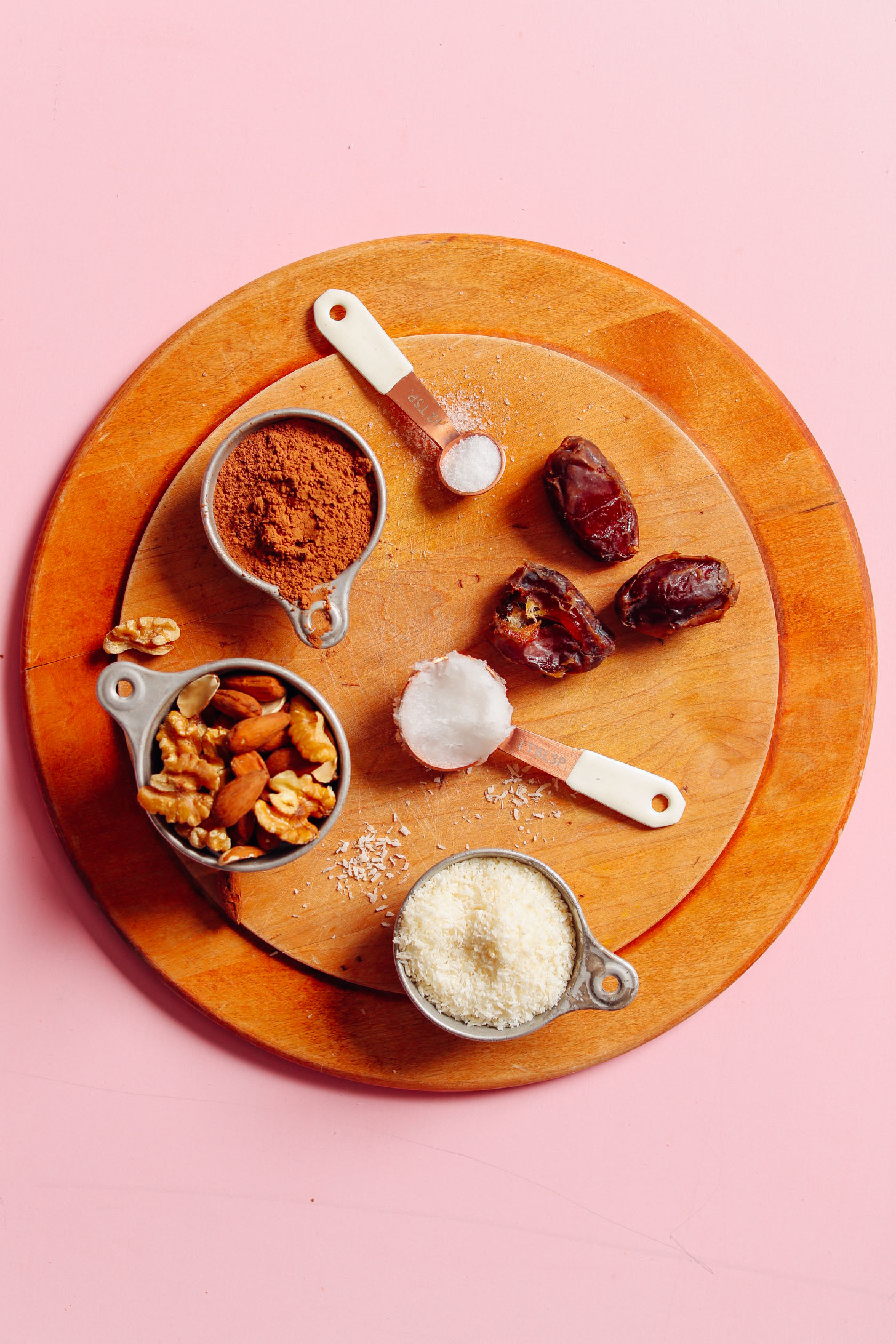 Wood cutting board with cocoa powder, nuts, coconut, coconut oil, dates, and sea salt for making our vegan Raw Oreo Cookies