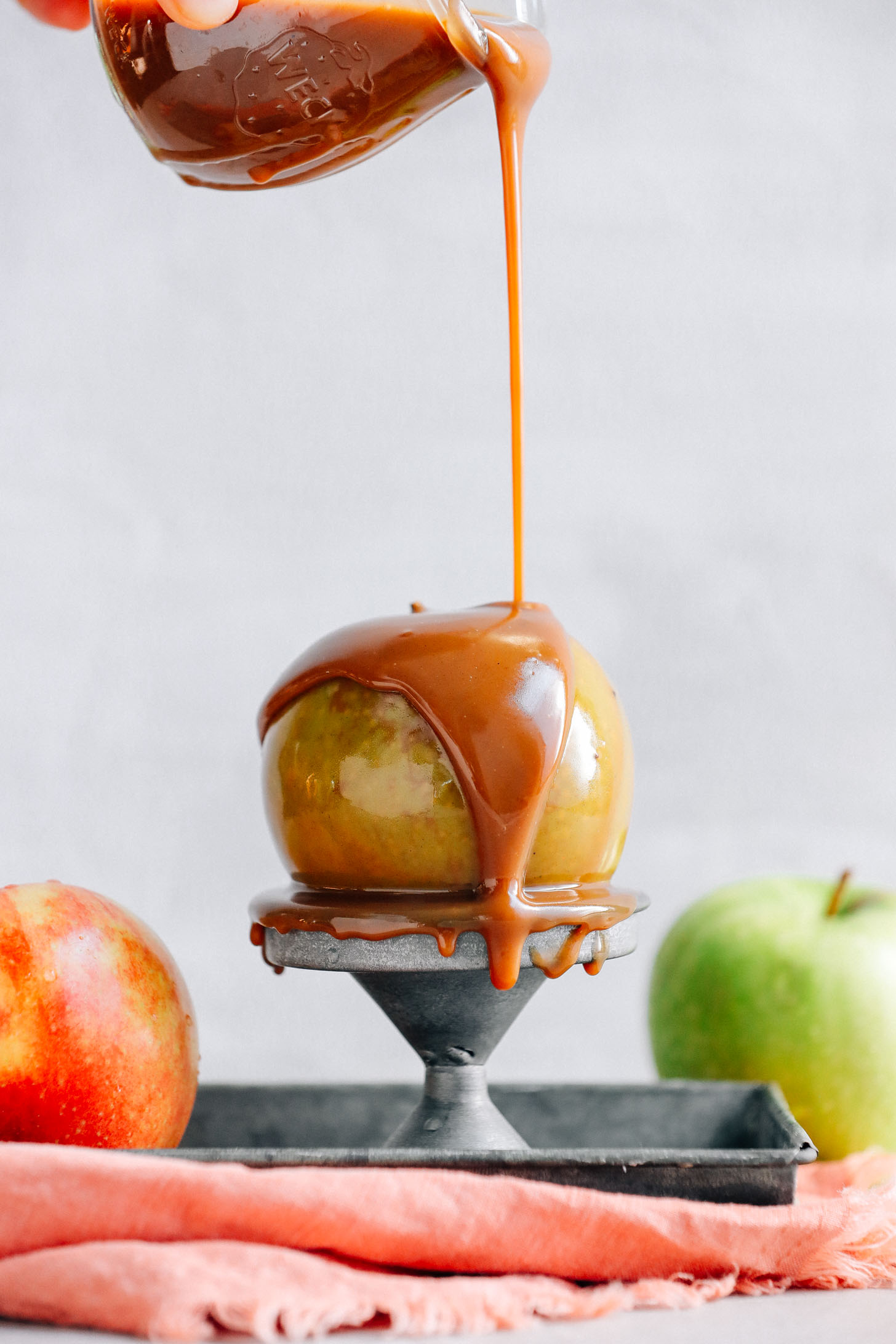 Drizzling Vegan Caramel Sauce onto an apple